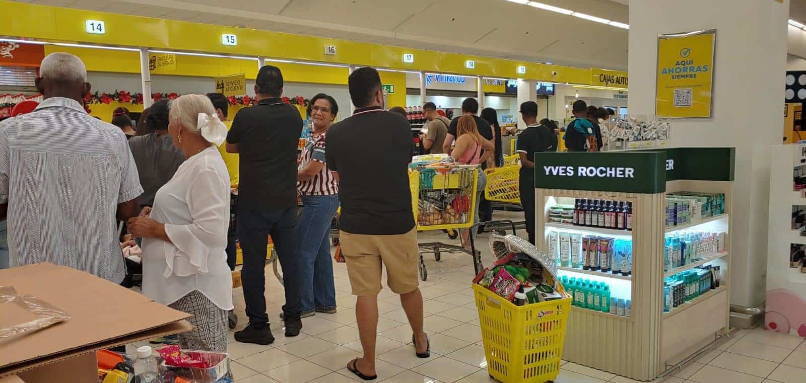 Personas haciendo fila en un supermercado para pagar sus compras.