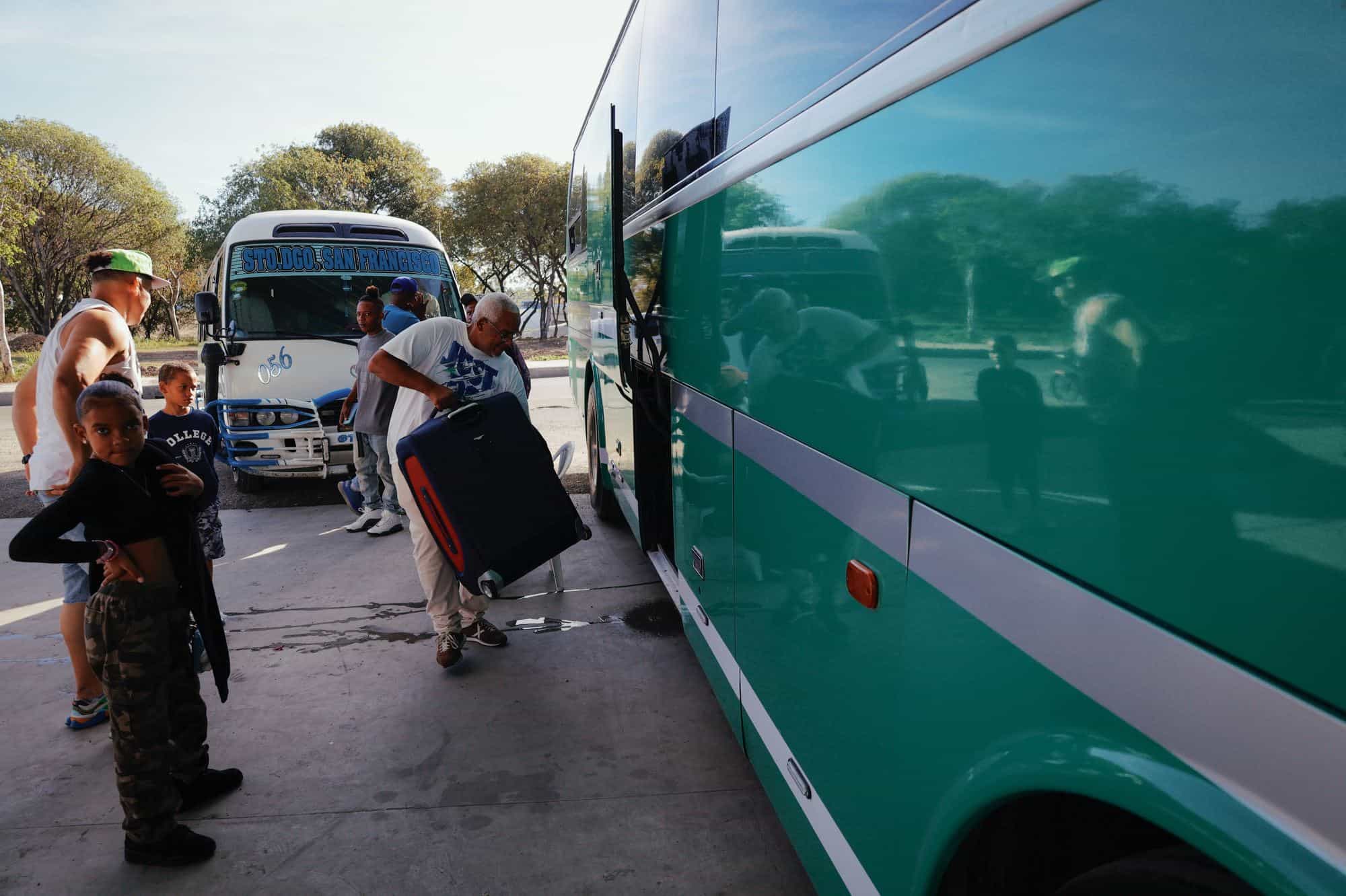 Un hombre deposita su equipaje en el interior de un autobús en el que viajará hasta La Vega para recibir el año 2025.