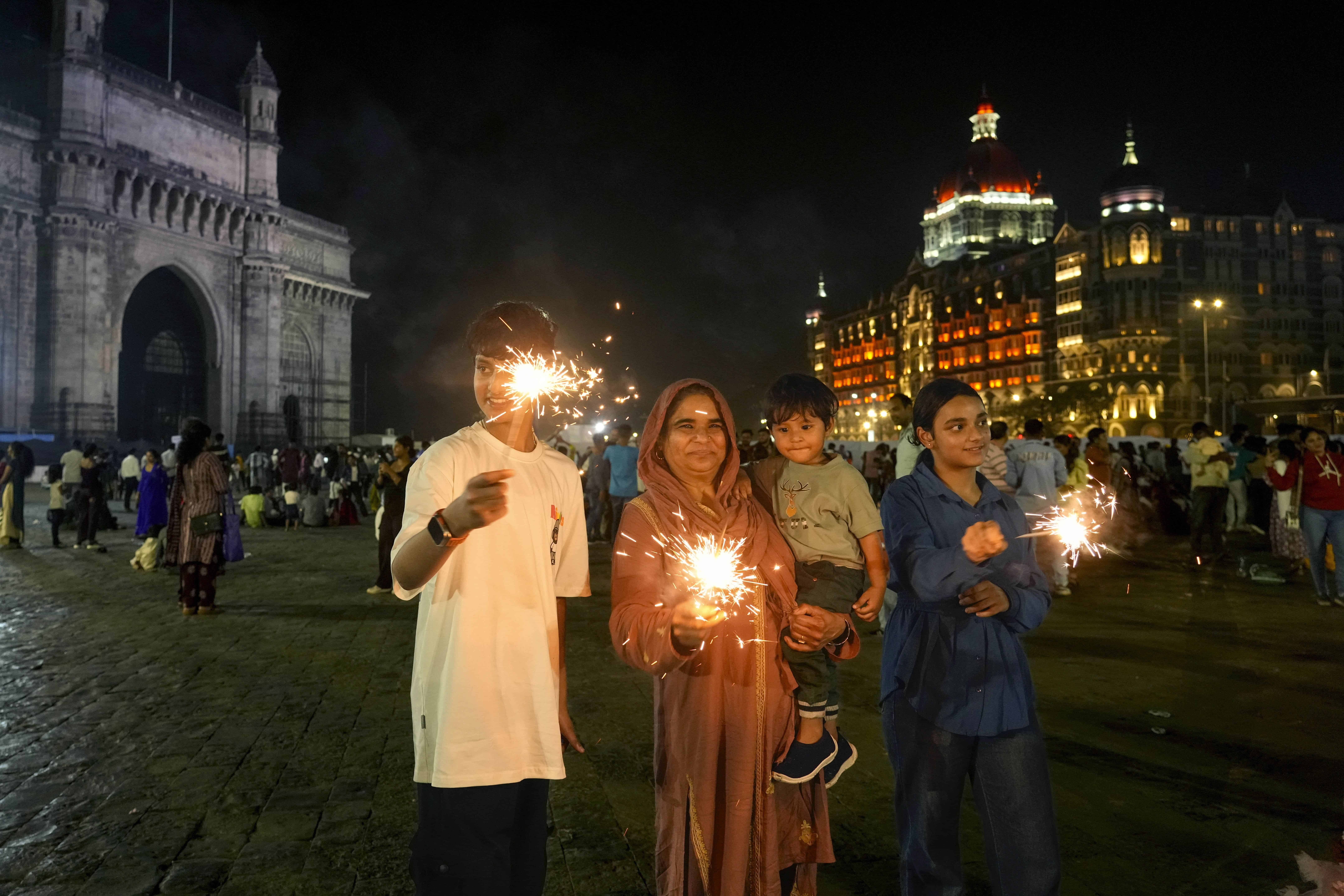 La gente enciende fuegos artificiales mientras celebran la víspera de Año Nuevo cerca de la icónica Puerta de la India, en Mumbai, India, el martes 31 de diciembre de 2024.