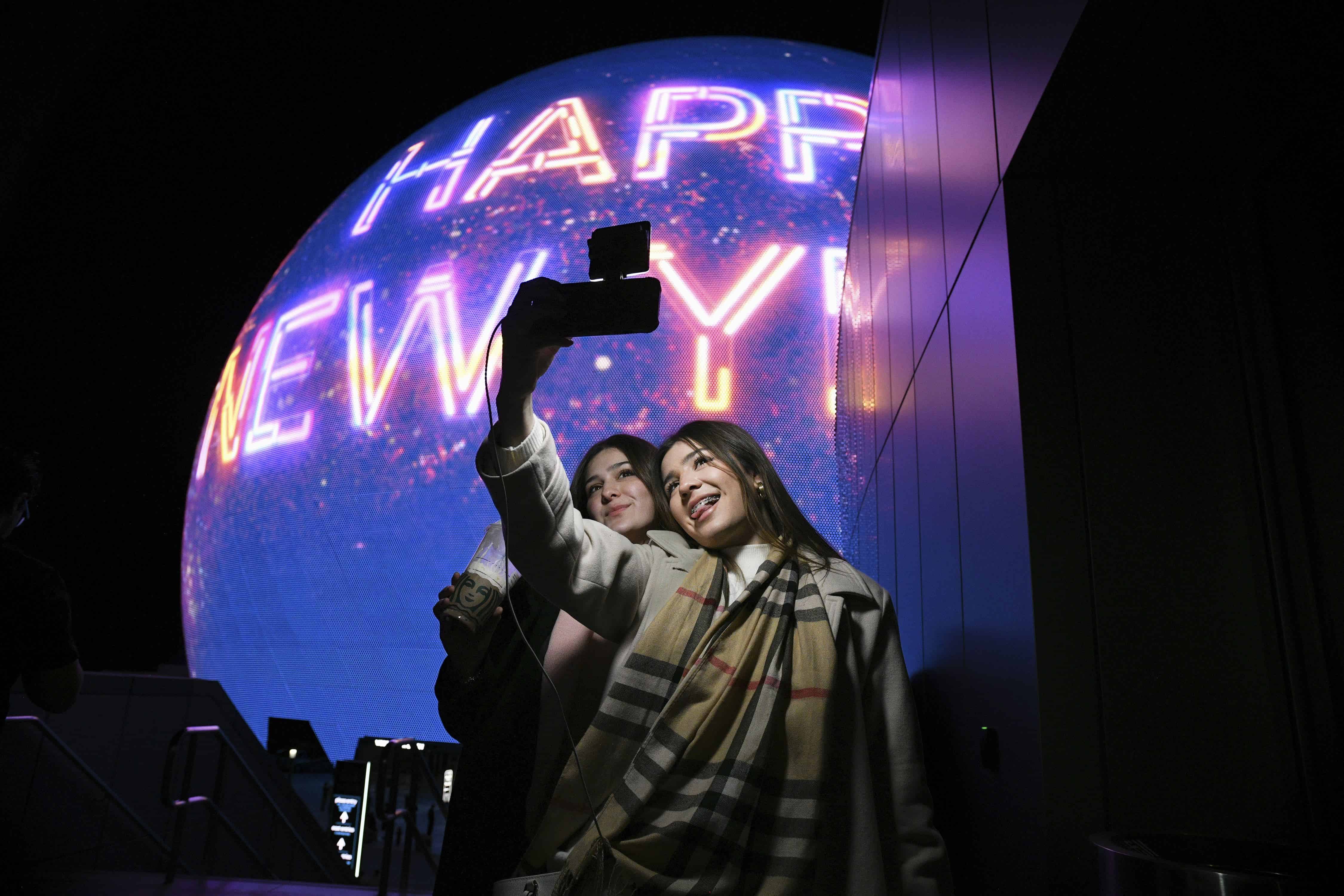 Paulina Mojica, a la izquierda, e Isabelle Mojica se toman un selfie mientras la Esfera muestra un mensaje de Feliz Año Nuevo el martes 31 de diciembre de 2024 en Las Vegas.
