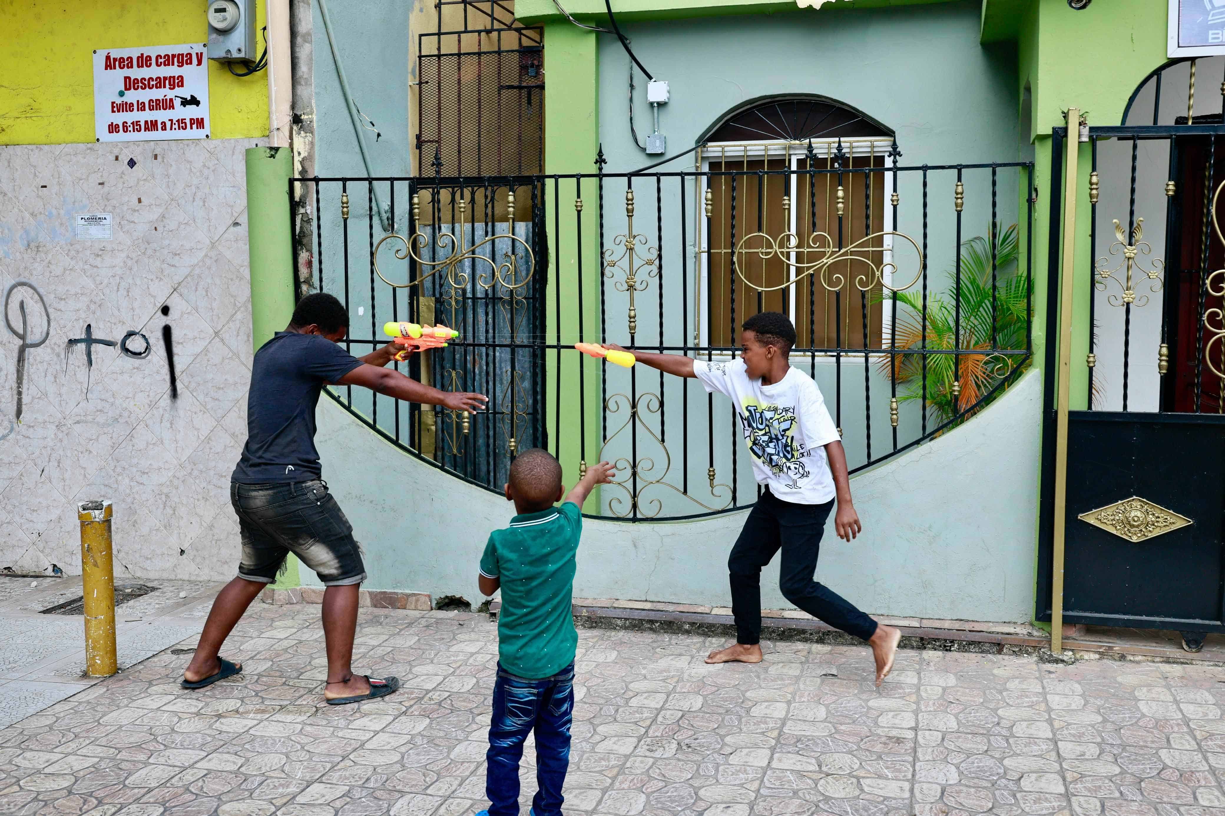 Tres niños juegan con sus juegos en un barrio de Santo Domingo Este.