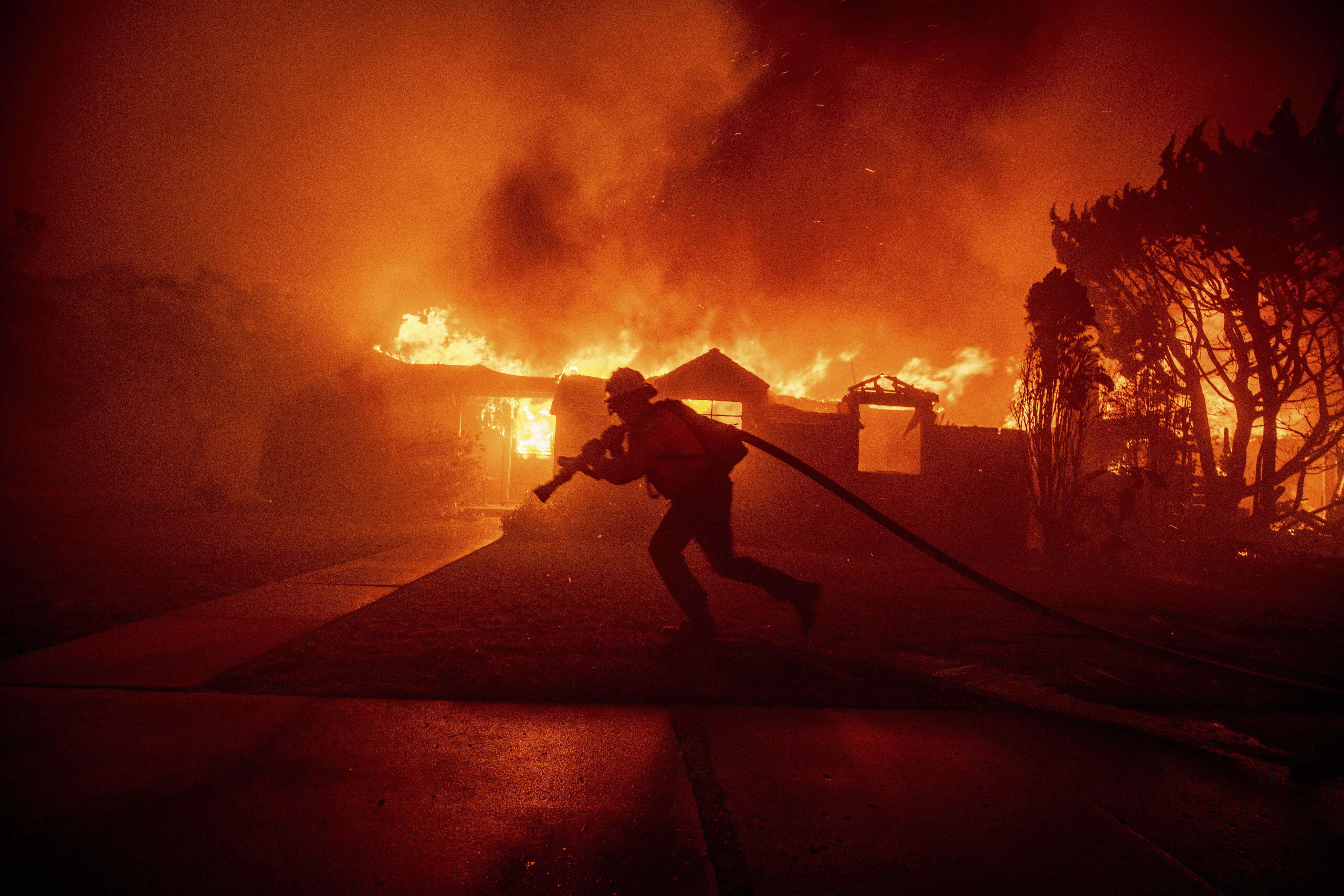 Un bombero lucha contra el incendio de Palisades mientras quema una estructura en el barrio de Pacific Palisades de Los Ángeles, el martes 7 de enero de 2025.