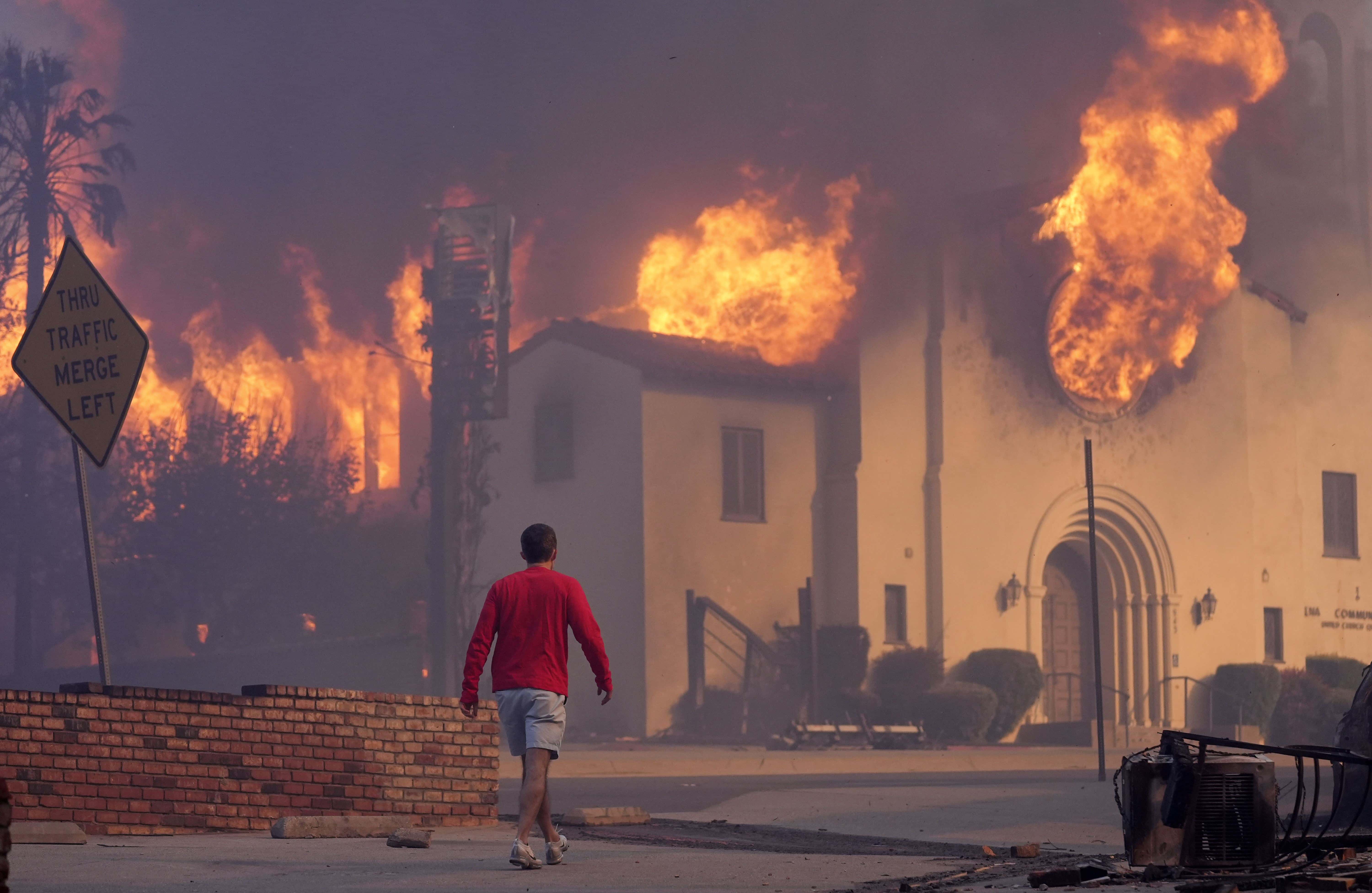 Un hombre camina frente a la iglesia comunitaria de Altadena en llamas, el miércoles 8 de enero de 2025, en la sección del centro de Altadena de Pasadena, California.