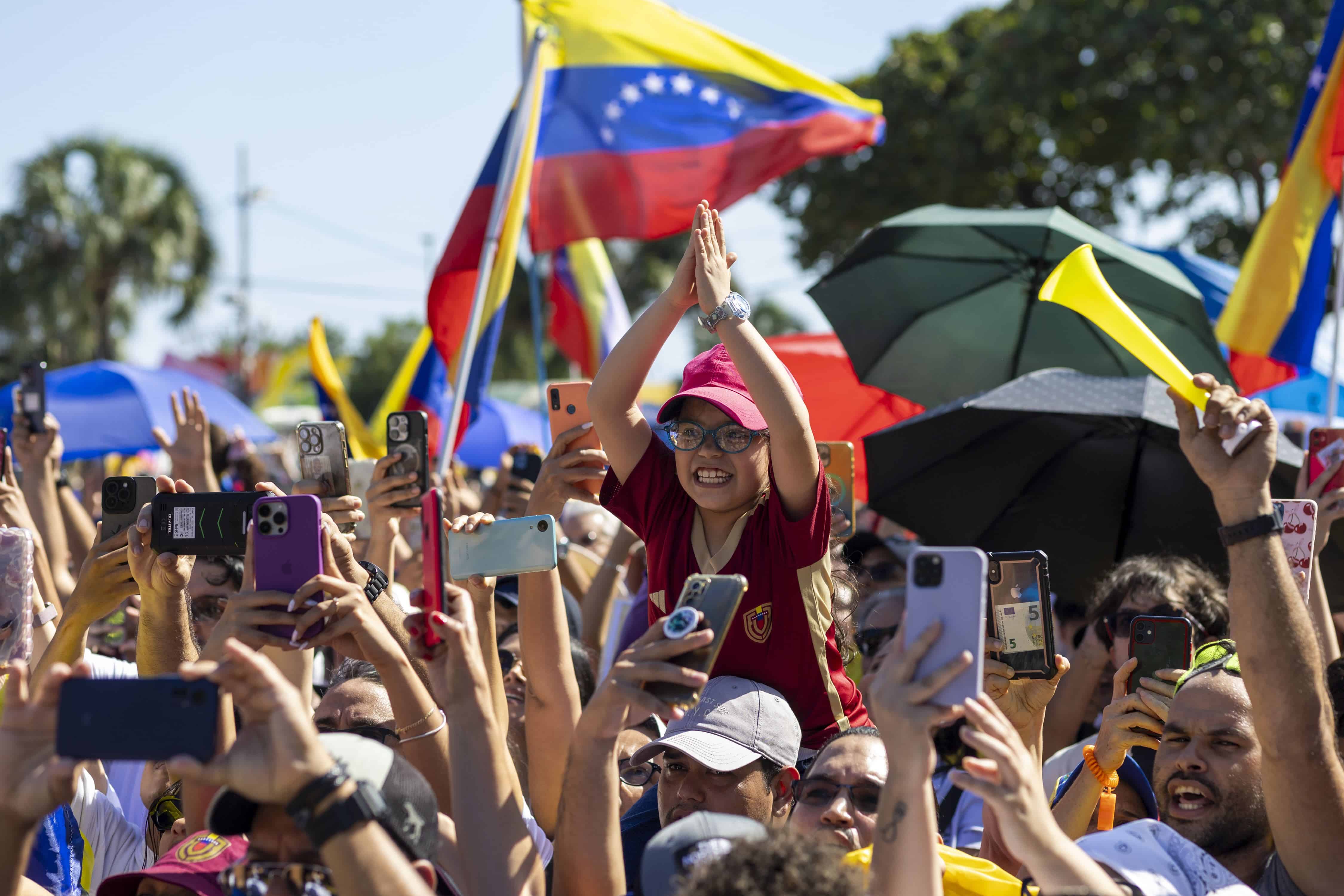 Una jovencita venezolana es cargada en hombros mientras espera la llegada de Edmundo González a la concentración convocada por la representación de Vente Venezuela en República Dominicana.