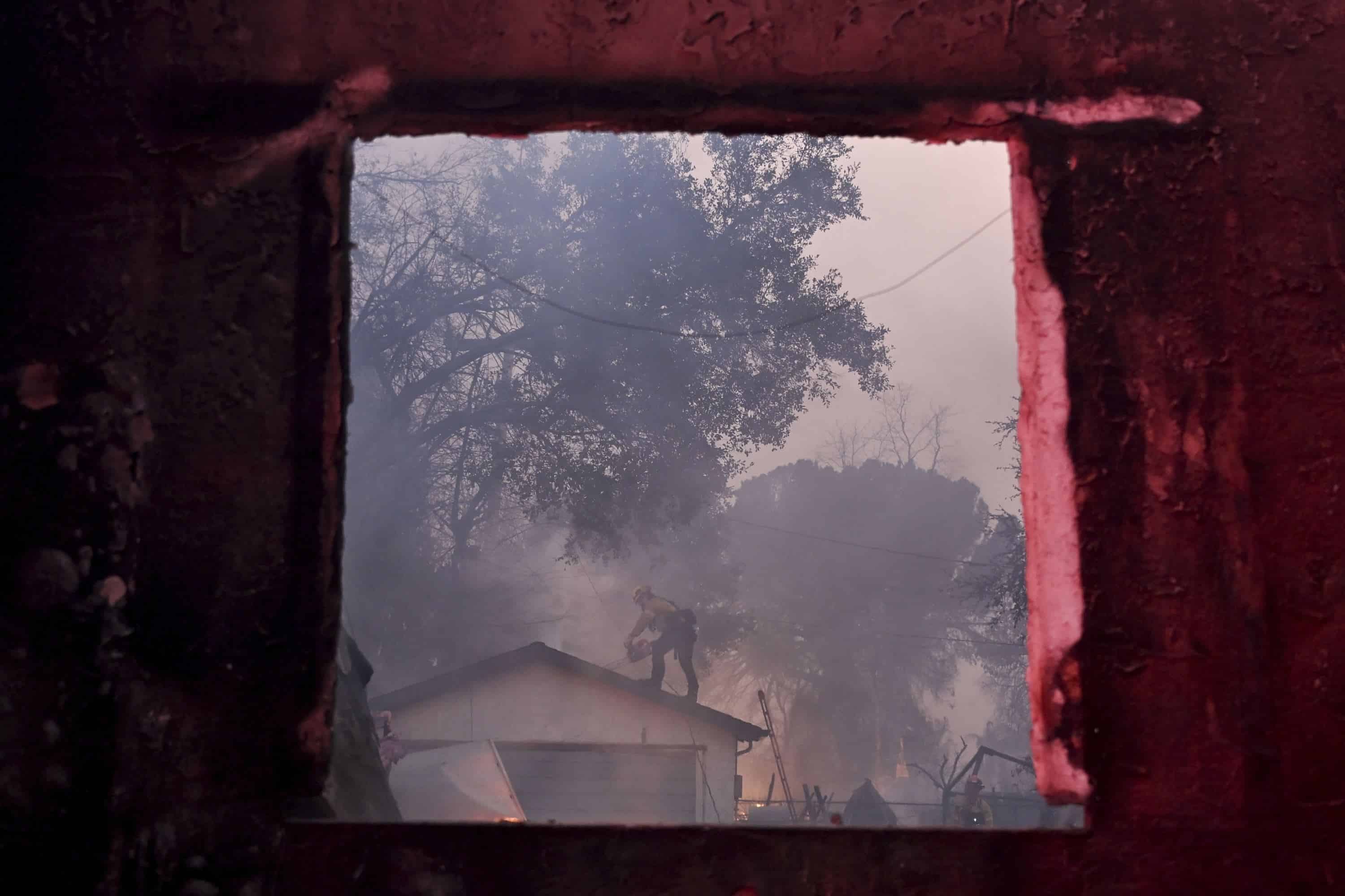 Un bombero es enmarcado a través de la ventana de una propiedad dañada por el fuego mientras lucha contra el incendio de Eaton el miércoles 8 de enero de 2025, en Altadena, California.