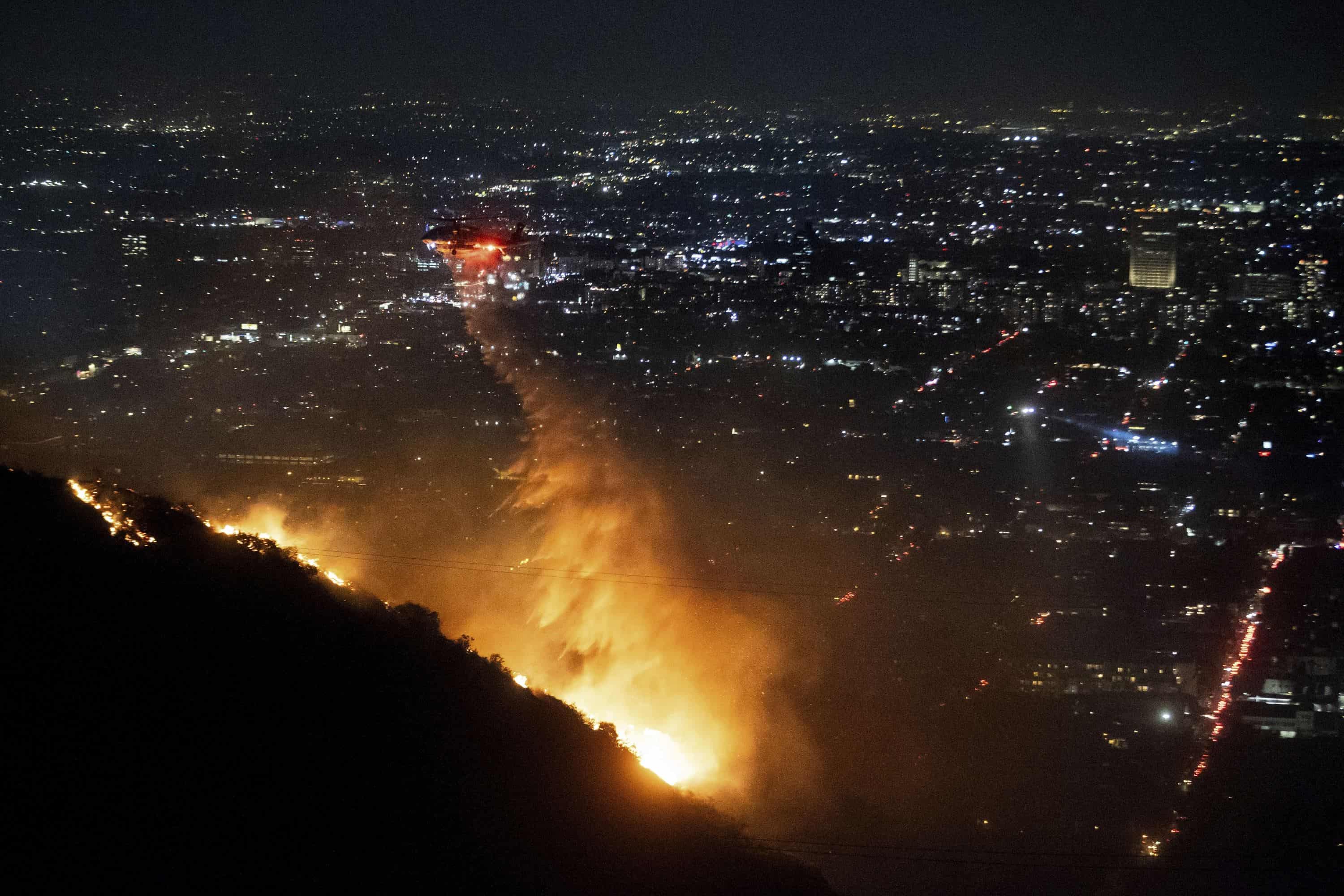 El agua es arrojada por un helicóptero sobre el Burning Sunset Fire en la sección Hollywood Hills de Los Ángeles, el miércoles 8 de enero de 2025.