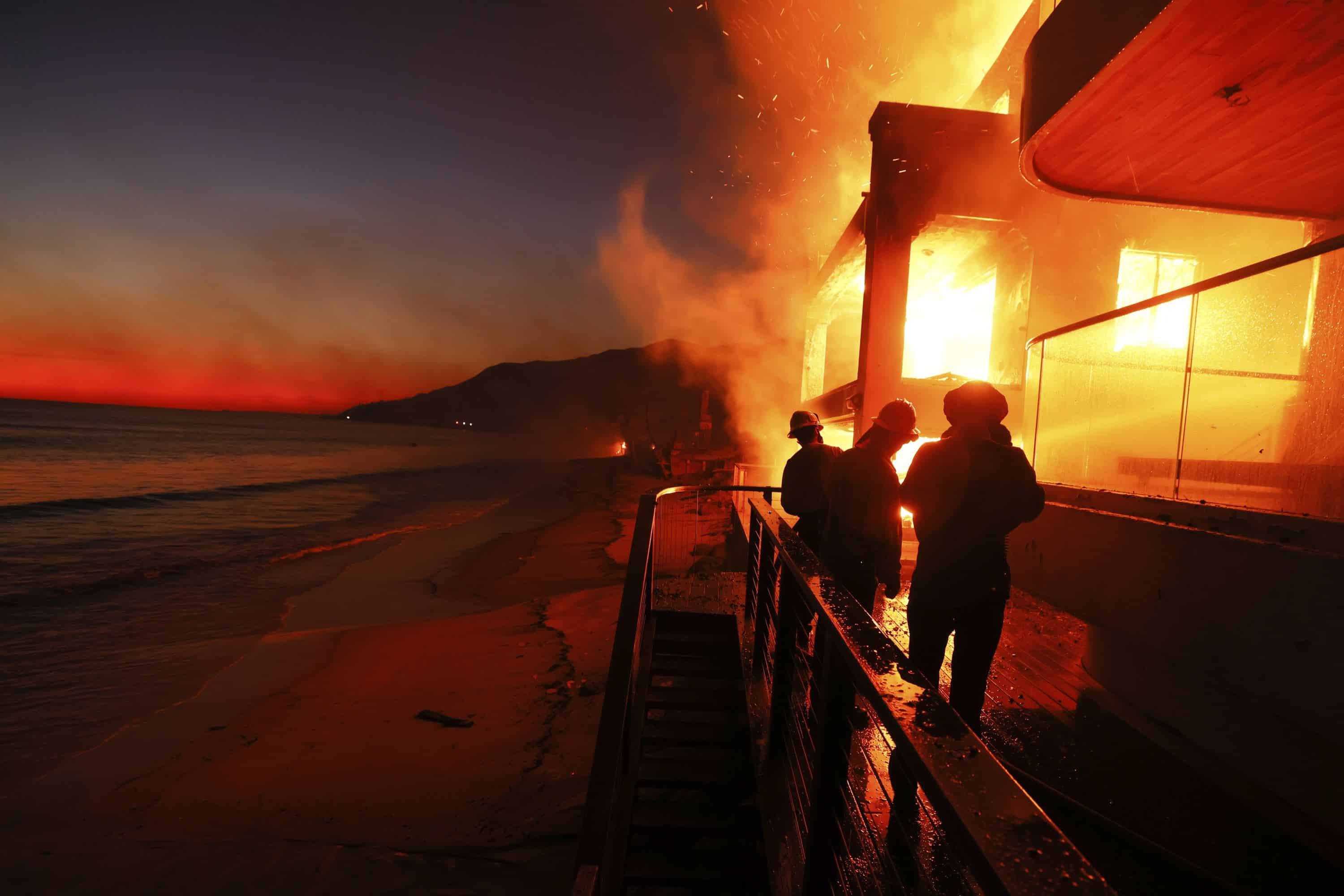 Los bomberos trabajan desde una cubierta mientras el incendio de Palisades quema una propiedad frente a la playa el miércoles 8 de enero de 2025 en Malibú, California.