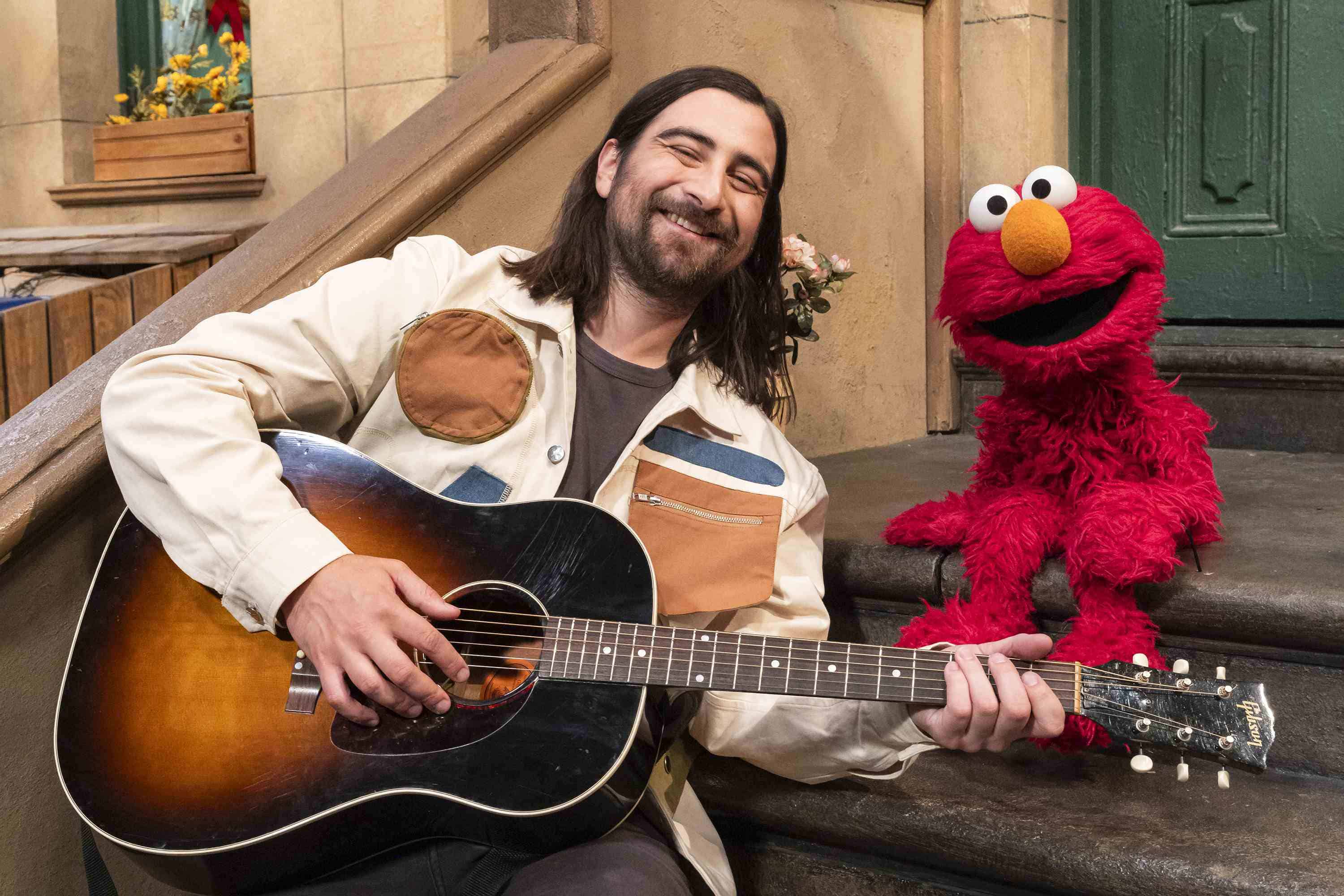 Esta imagen proporcionada por Sesame Workshop muestra al cantante Noah Kahan, a la izquierda, con el personaje de los muppets Elmo en el set de Sesame Street.