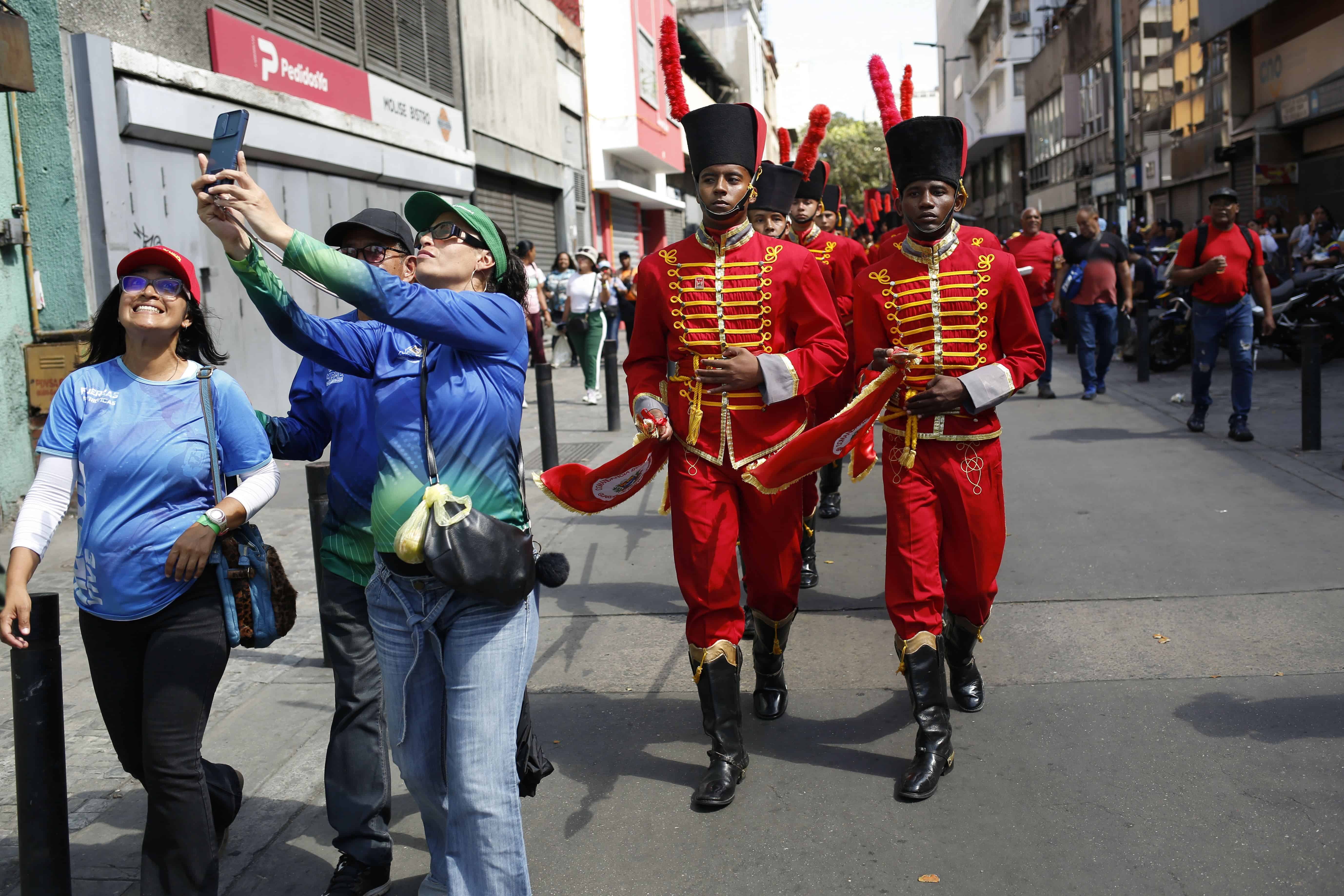 Los partidarios del gobierno se toman un selfie con guardias de honor detrás de ellos marchando después de la ceremonia de juramento del presidente venezolano Nicolás Maduro para un tercer mandato en Caracas, Venezuela, el 10 de enero de 2025.