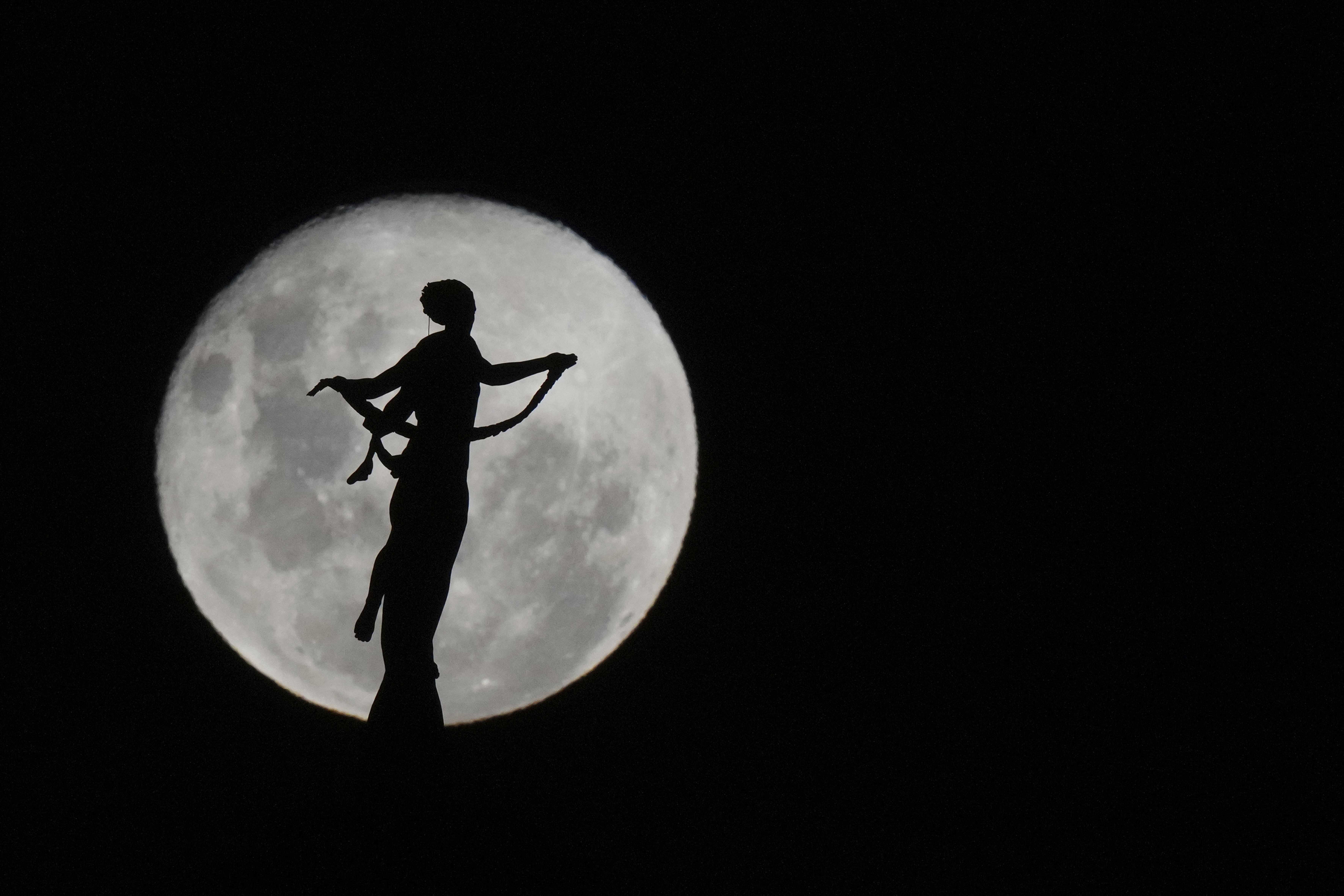 La luna del lobo se levanta detrás de la silueta de la estatua de la Paz Victoriosa, en Asunción, Paraguay, el 14 de enero de 2025.