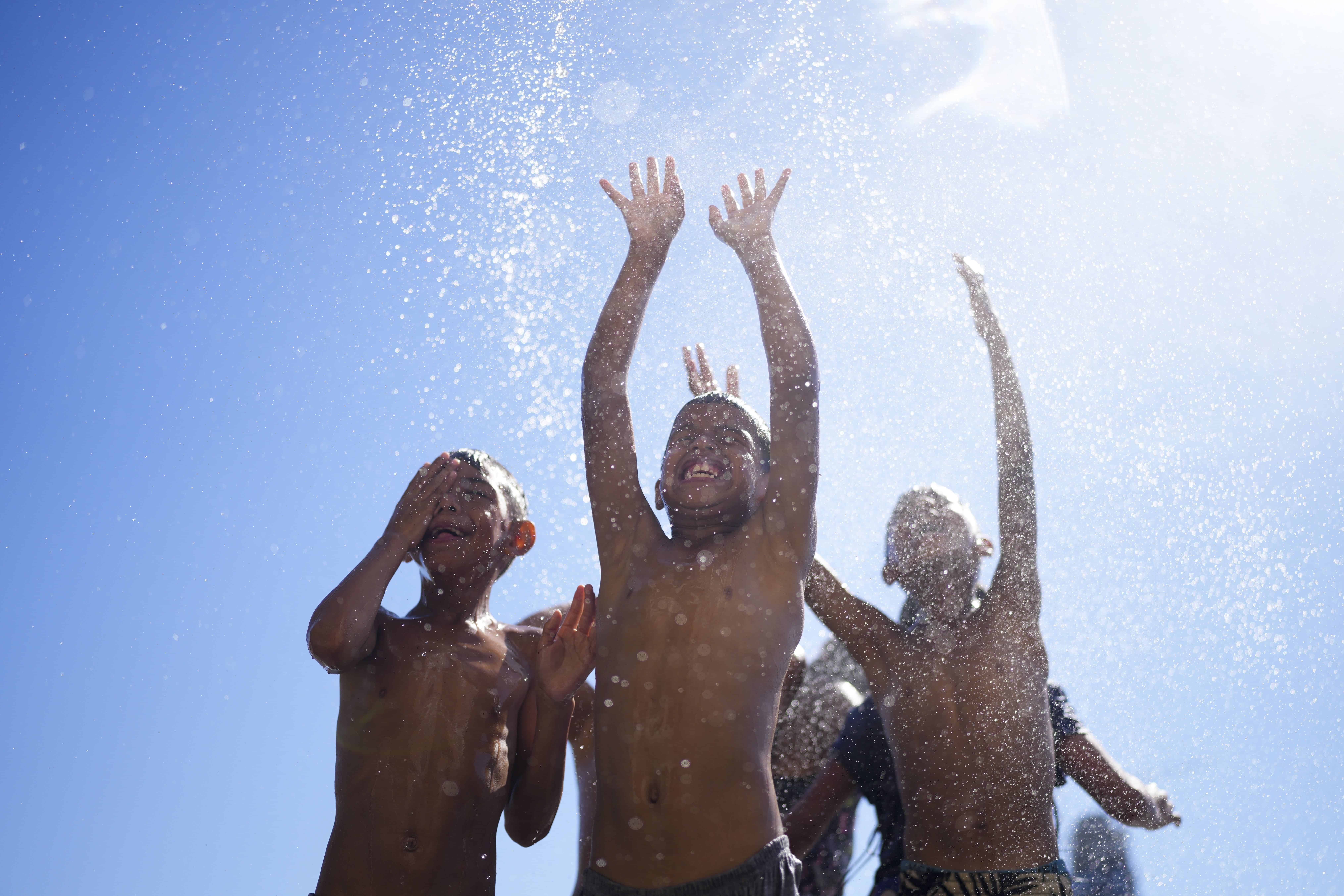 Los niños juegan en la pulverización de una manguera de agua durante el verano en Buenos Aires, Argentina, 13 de enero de 2025.