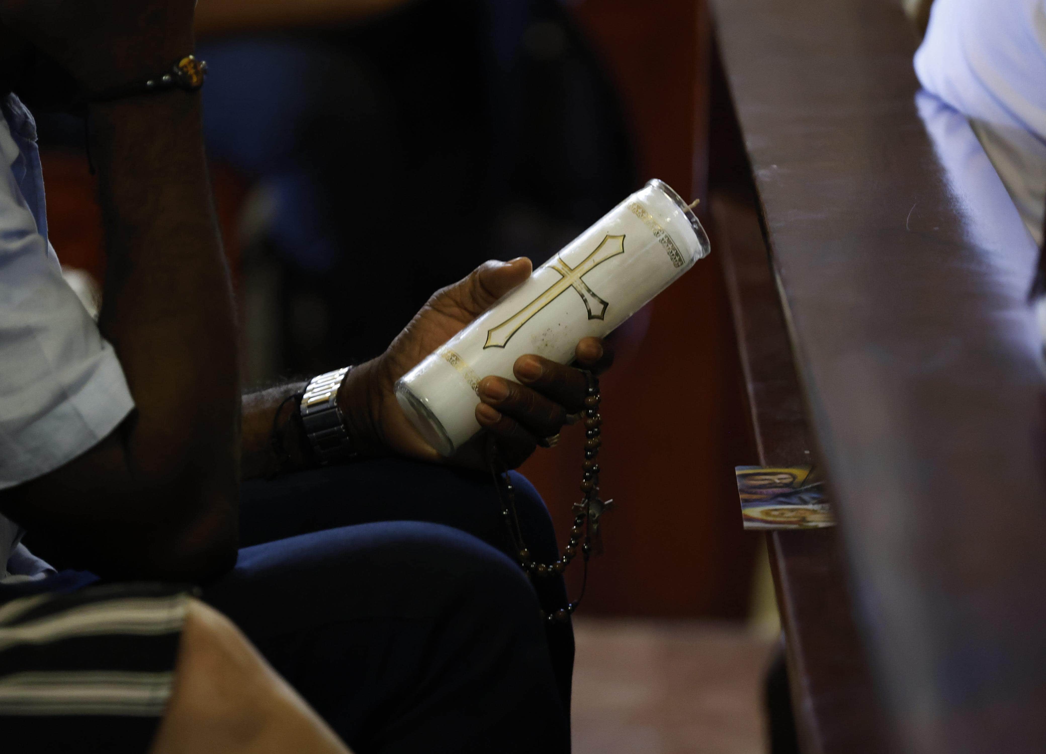 Feligrés sujetando un velón durante la misa en la Basílica de Higüey.