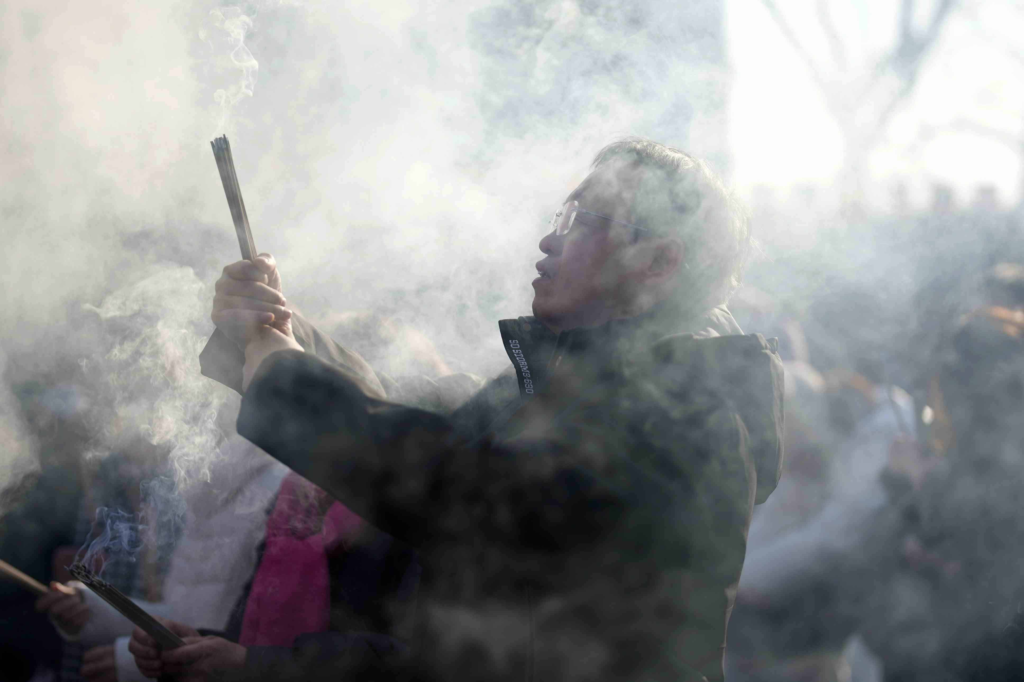 Un hombre sostiene varillas de incienso mientras reza en el primer día del Año Nuevo Lunar en el templo Lama de Beijing, el miércoles 29 de enero de 2025. 