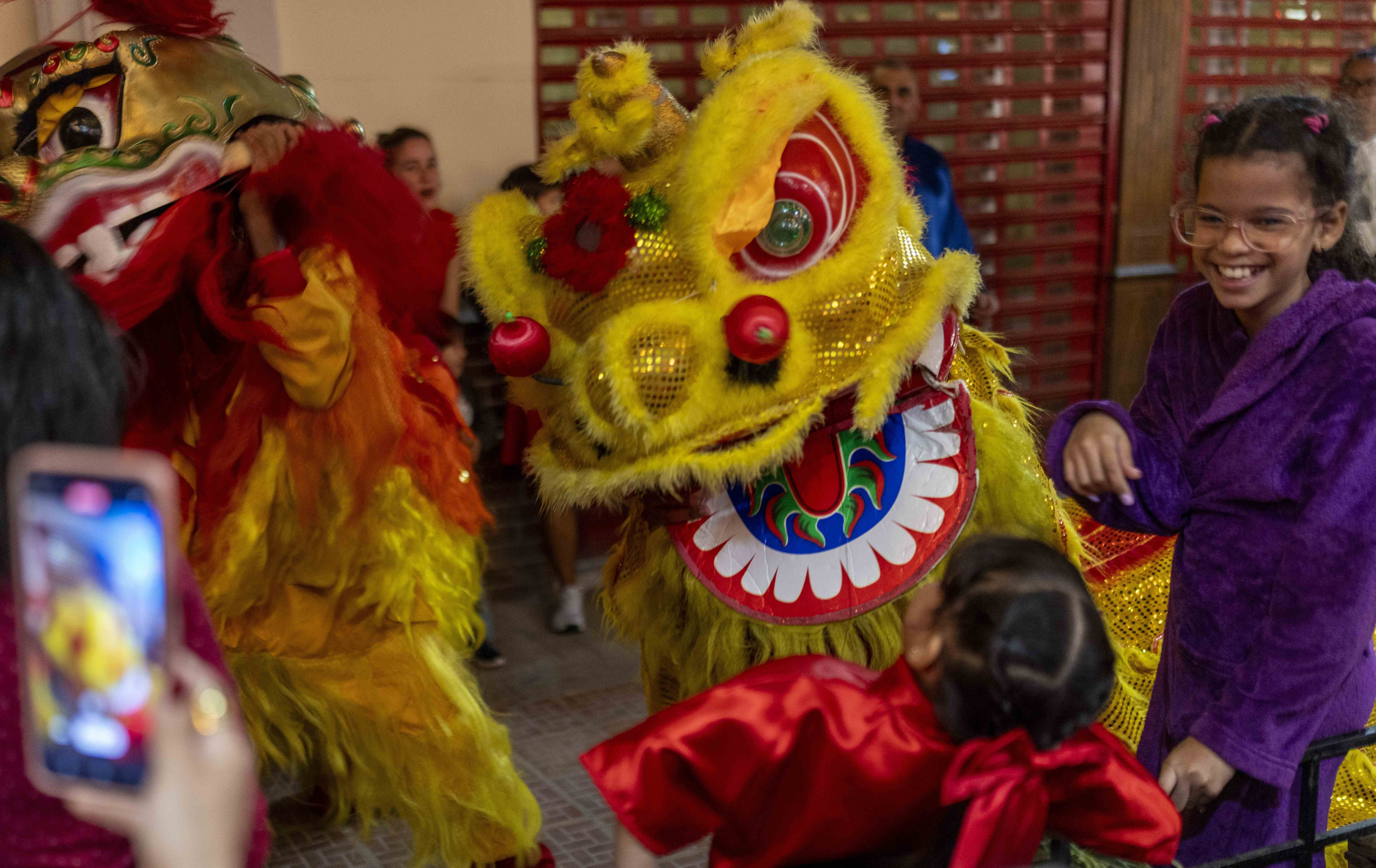 Un artista vestido de león asusta a una niña mientras participa en la danza tradicional del león al inicio de las celebraciones del Año Nuevo Lunar en La Habana, el martes 28 de enero de 2025. 