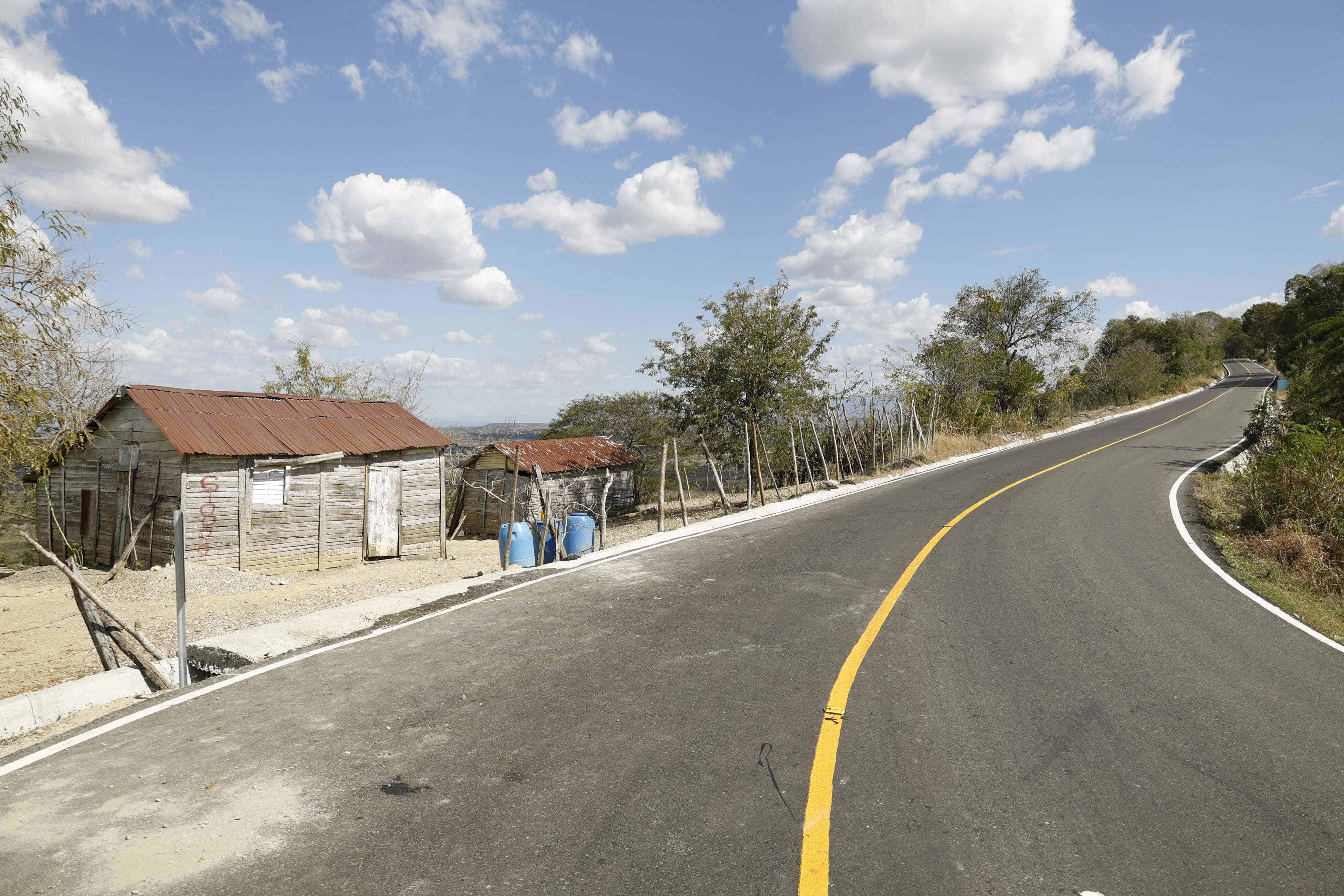 Contraste entre las casas de madera y la carretera de Comendador-Guaroa-Macasías.