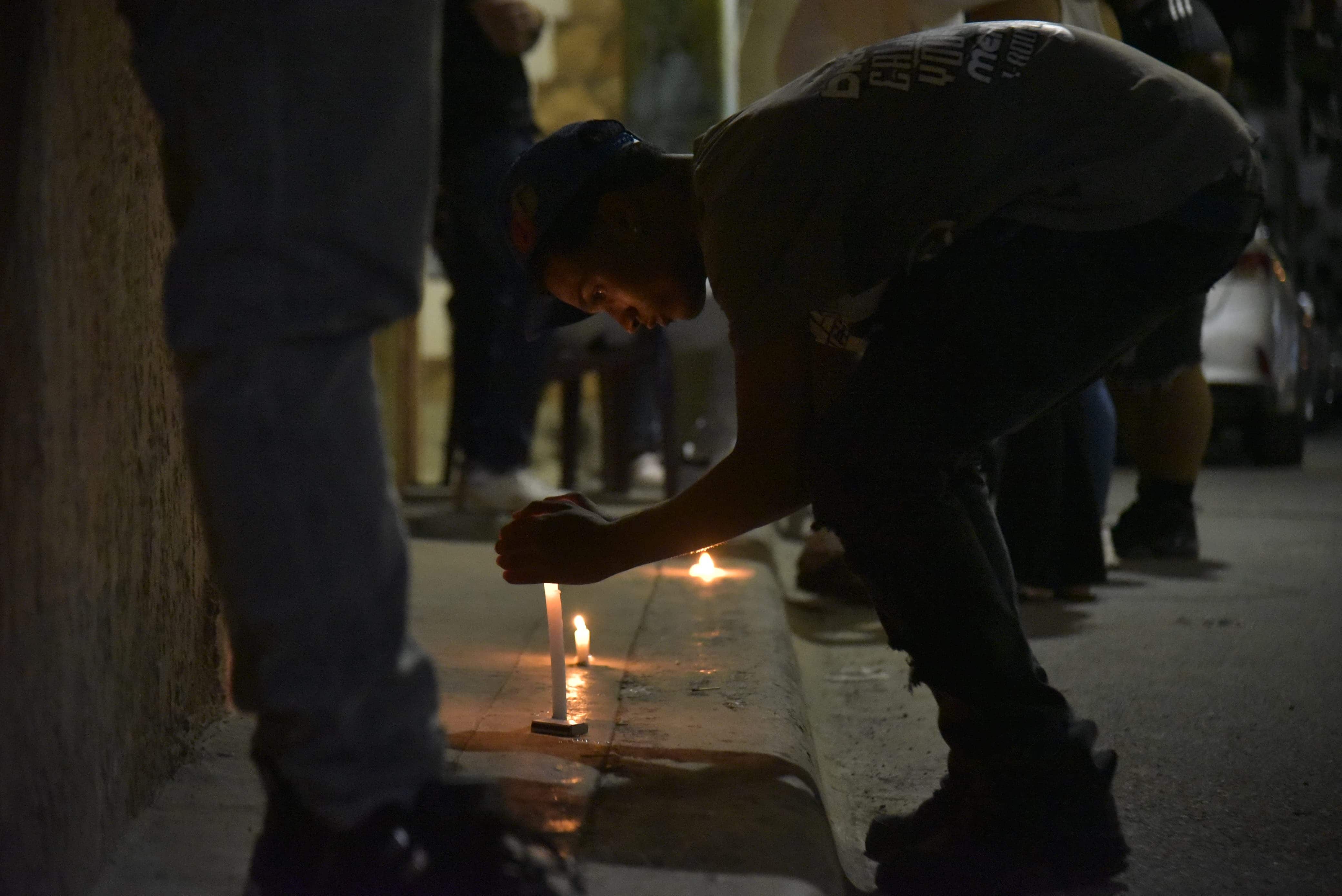 Una persona de la comunidad enciende una vela por uno de los jóvenes asesinado en Herrera. 