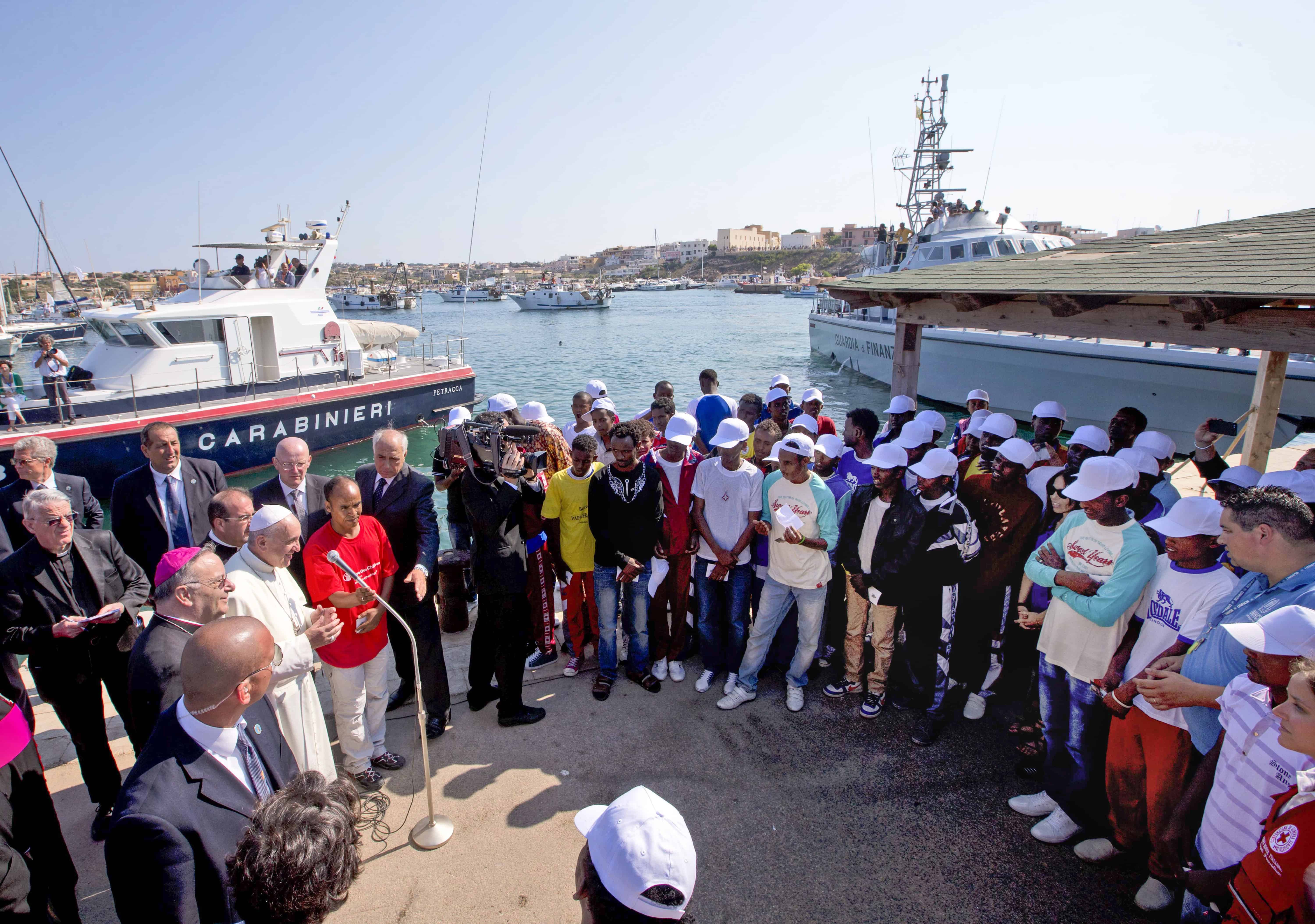 El papa Francisco (izquierda), habla con migrantes, con gorras blancas, durante una visita a la isla de Lampedusa, en el sur de Italia, el 8 de julio de 2013. 