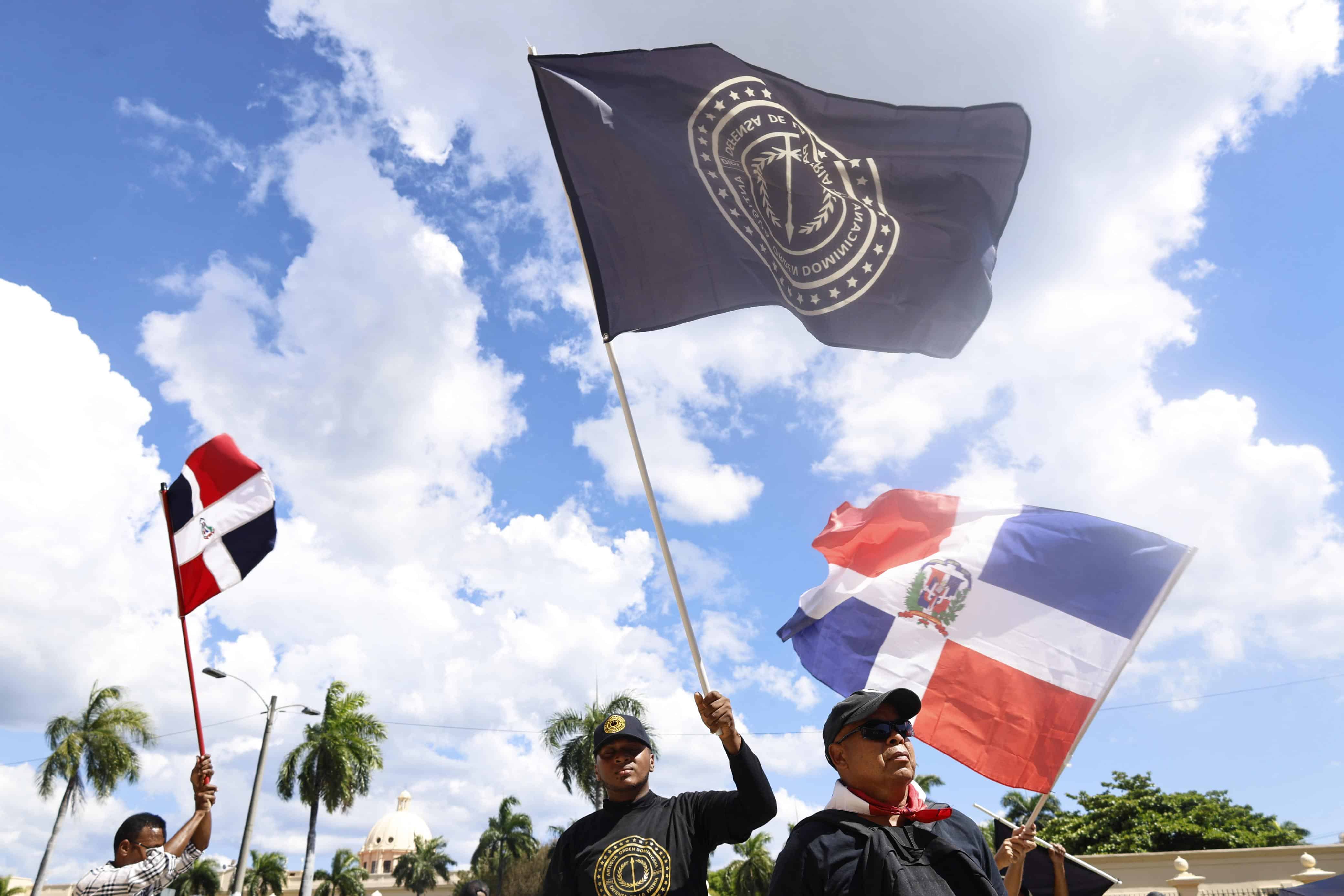 Protestantes con banderas participan en la marcha contra la inmigración haitiana.