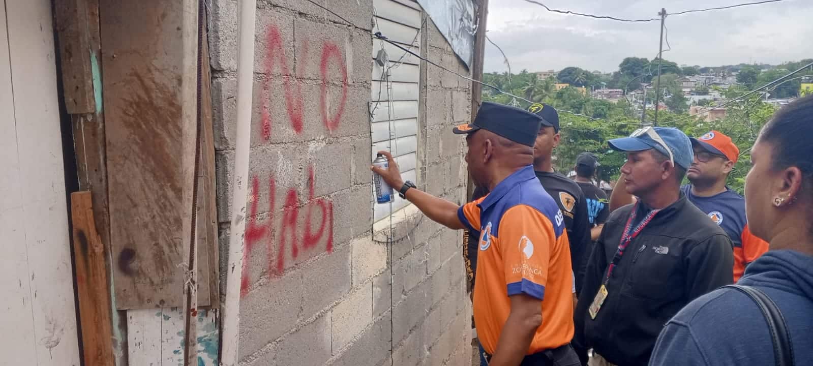 Director provincial de la Defensa Civil, Francisco Arias, colocando letreros de advertencia en las casas que corren el riesgo de derrumbe. 