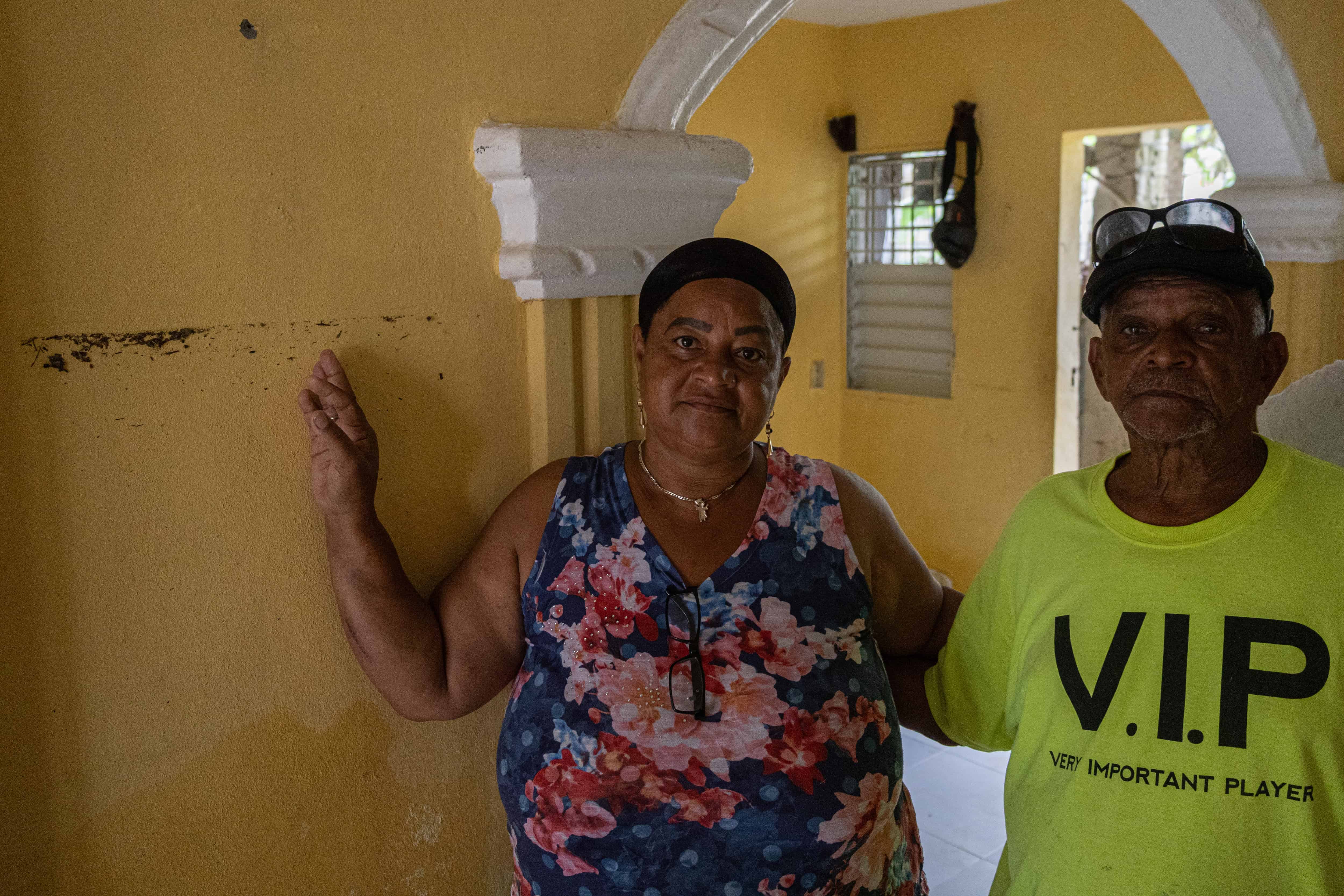 Alicia Sánchez y su padre, con la marca del nivel del agua en la pared.