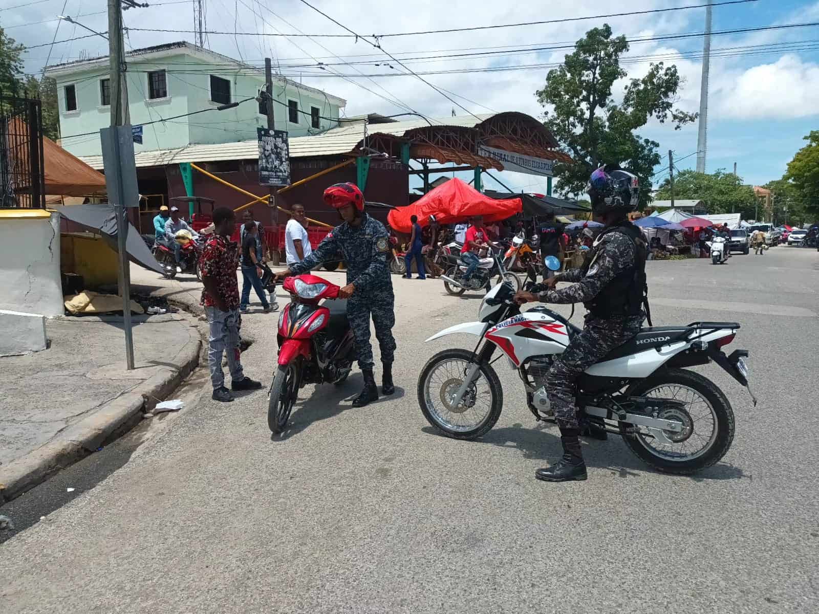 Dos agentes policiales retienen un motor a un joven por falta de papeles.