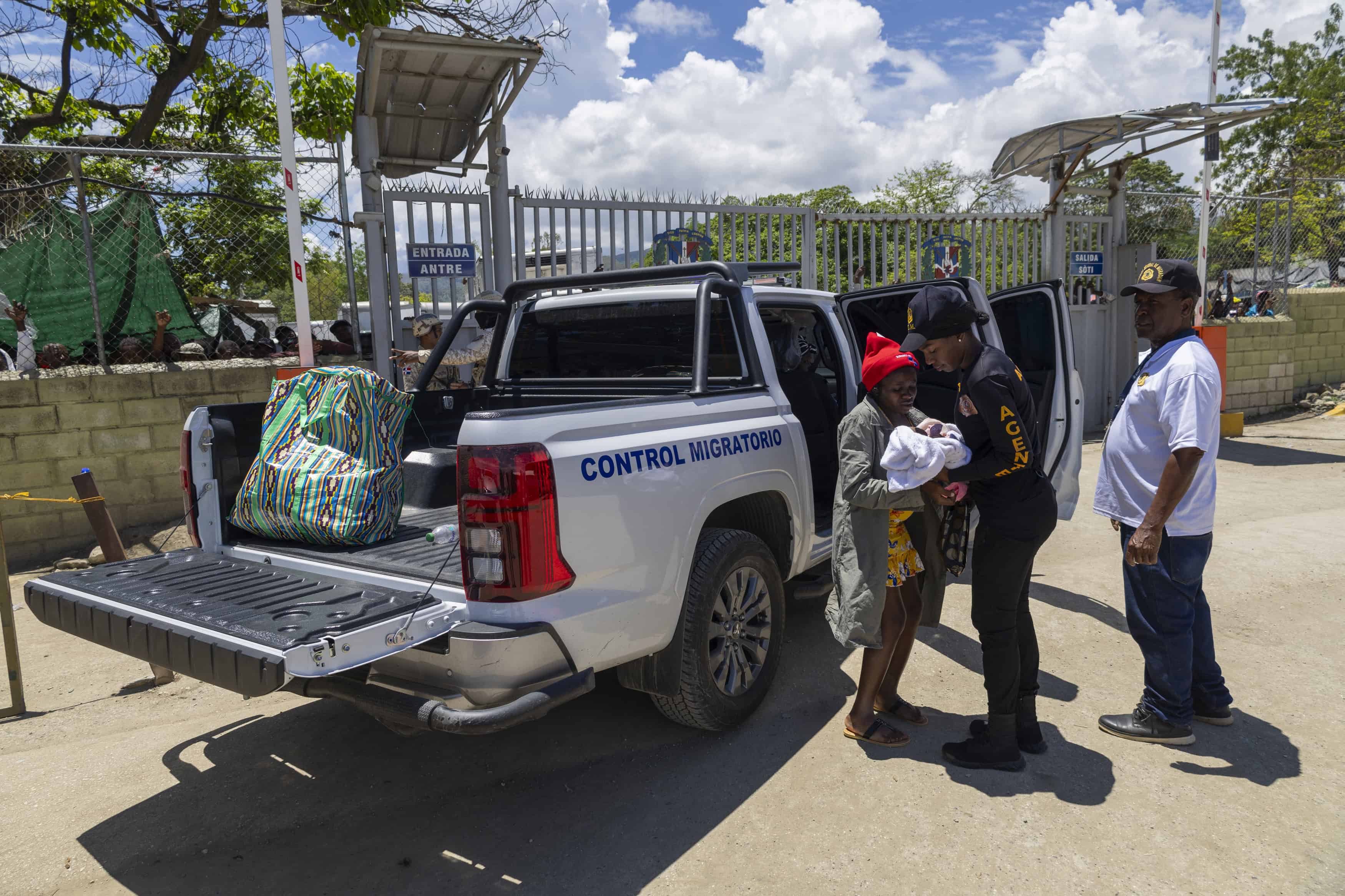 Una madre haitiana, con su bebé de pocos meses, saliendo de un carro de Migración, mientras es deportada a su país.