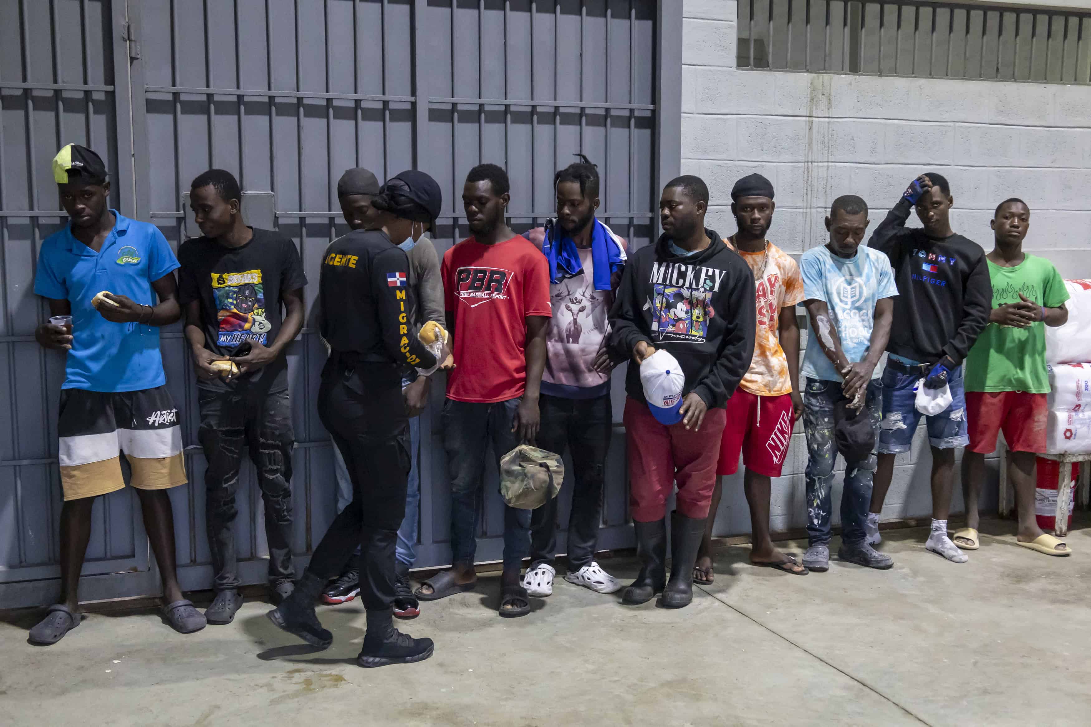 Fila de hombres haitianos, recibiendo el desayuno antes de subir al camión.