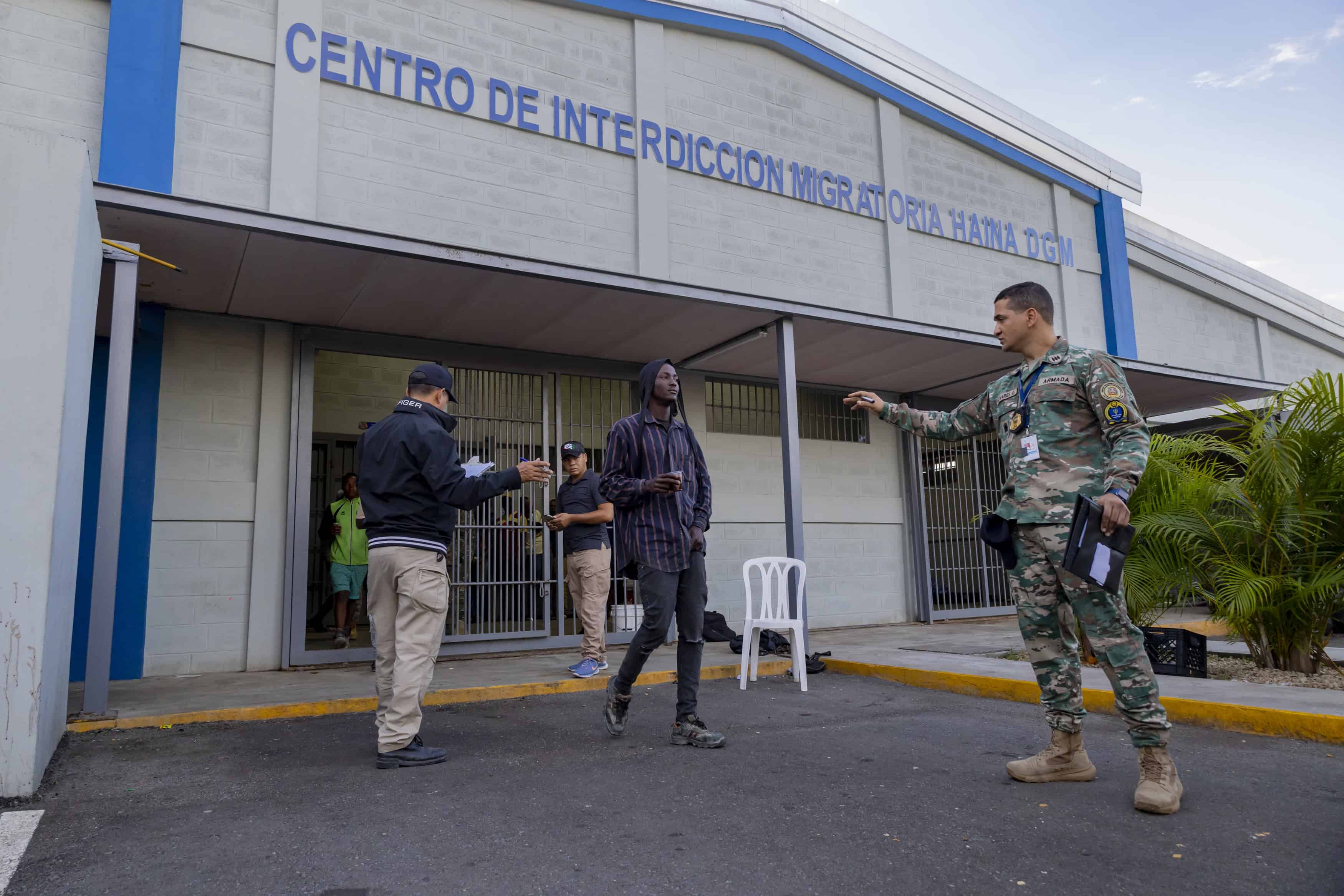 Un militar vigila la fila y cuenta a los haitianos que suben al camión.