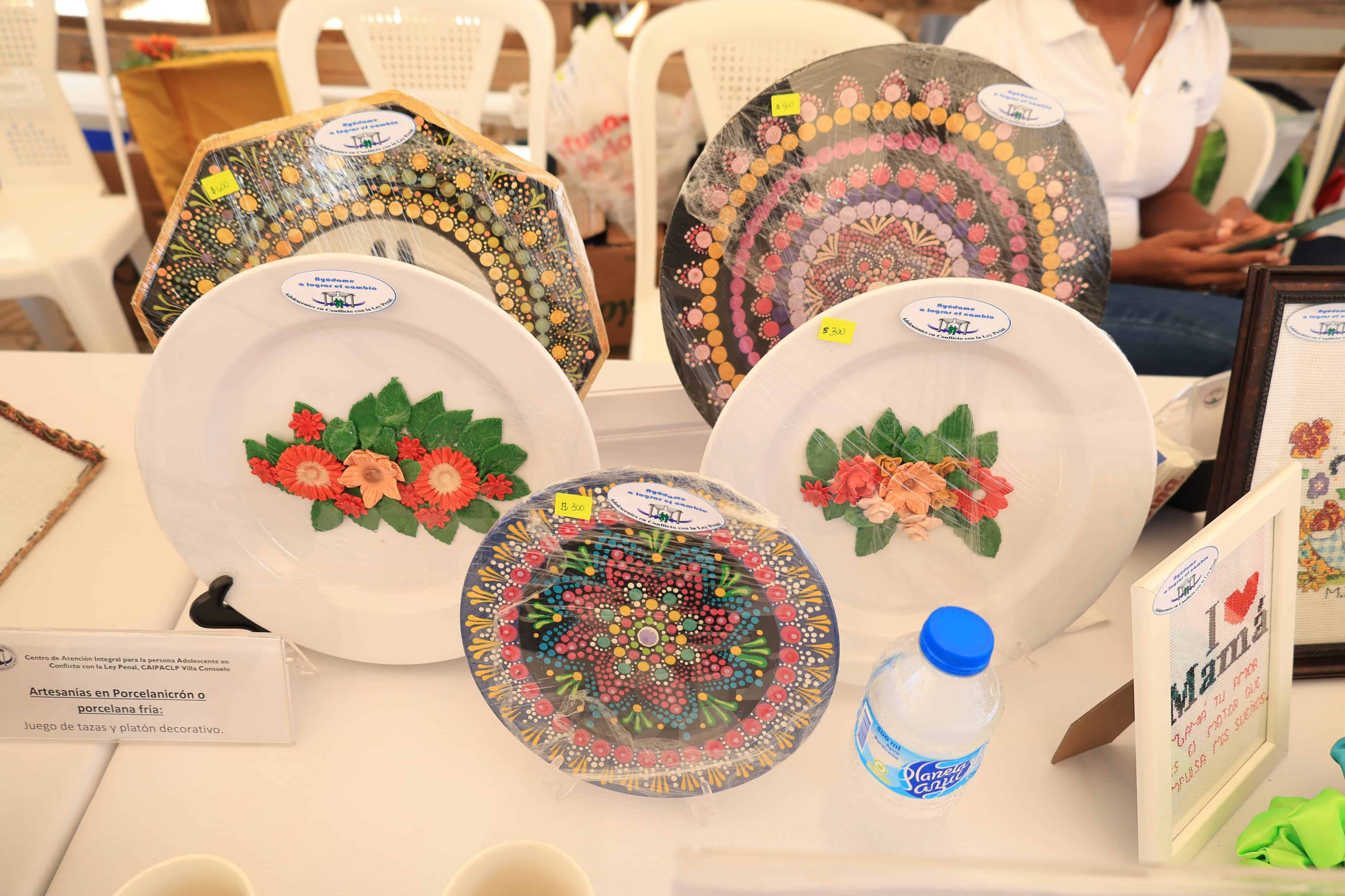 Artículos elaborados por los reclusos, algunos adornados con flores y la bandera dominicana son exhibidos la tercera Feria Artesanal y de Producción del Sistema Penitenciario, este 23 de mayo de 2025. 