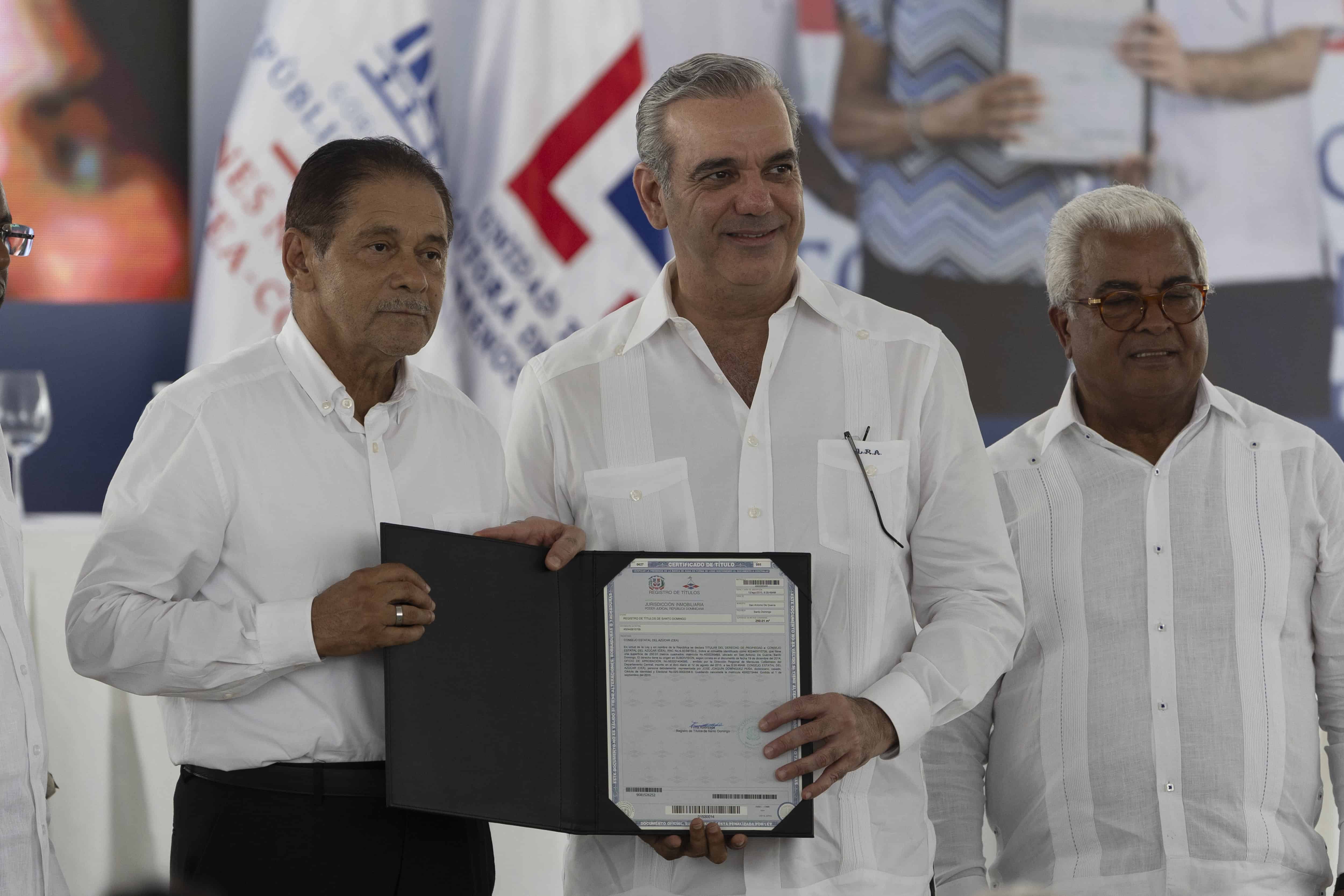 El presidente Luis Abinader (centro) y el director de Bienes Nacionales, Rafael Burgos (derecha), en el acto de entrega de 850 títulos de propiedad en el Gran Santo Domingo este 30 de mayo de 2025.