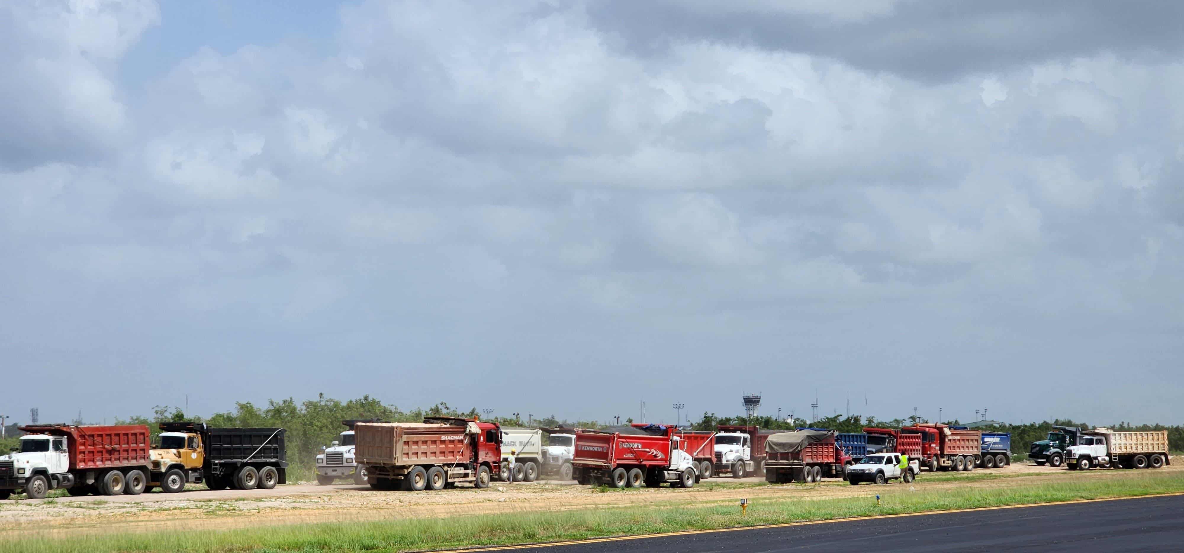Camiones con materiales de construcción sobre el terreno del AILA, en el que se le da mantenimiento a la pista de aterrizaje, como parte de las mejoras a las instalaciones del aeropuerto.