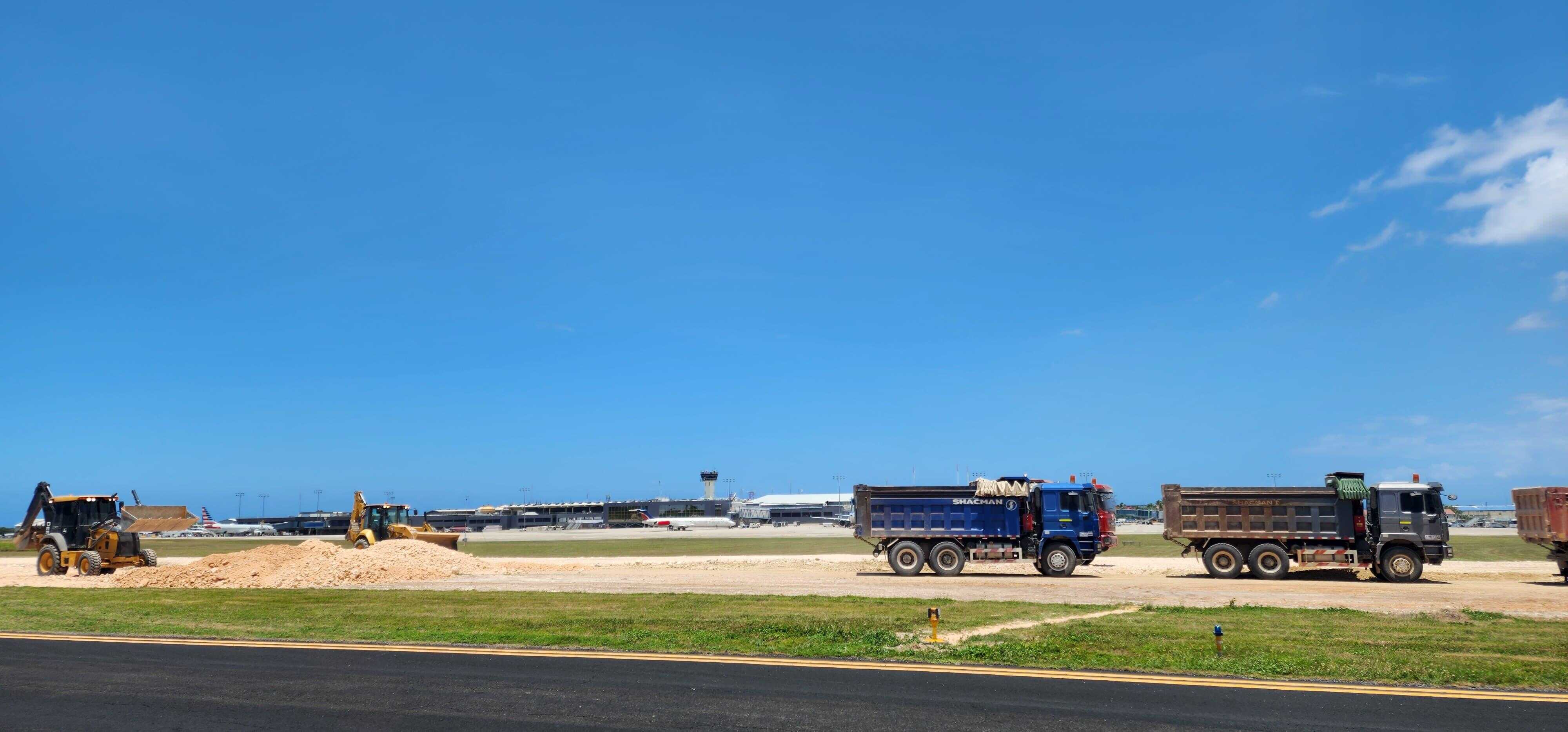 Camiones con materiales de construcción sobre el terreno del AILA, en el que se le da mantenimiento a la pista de aterrizaje, como parte de las mejoras a las instalaciones del aeropuerto.