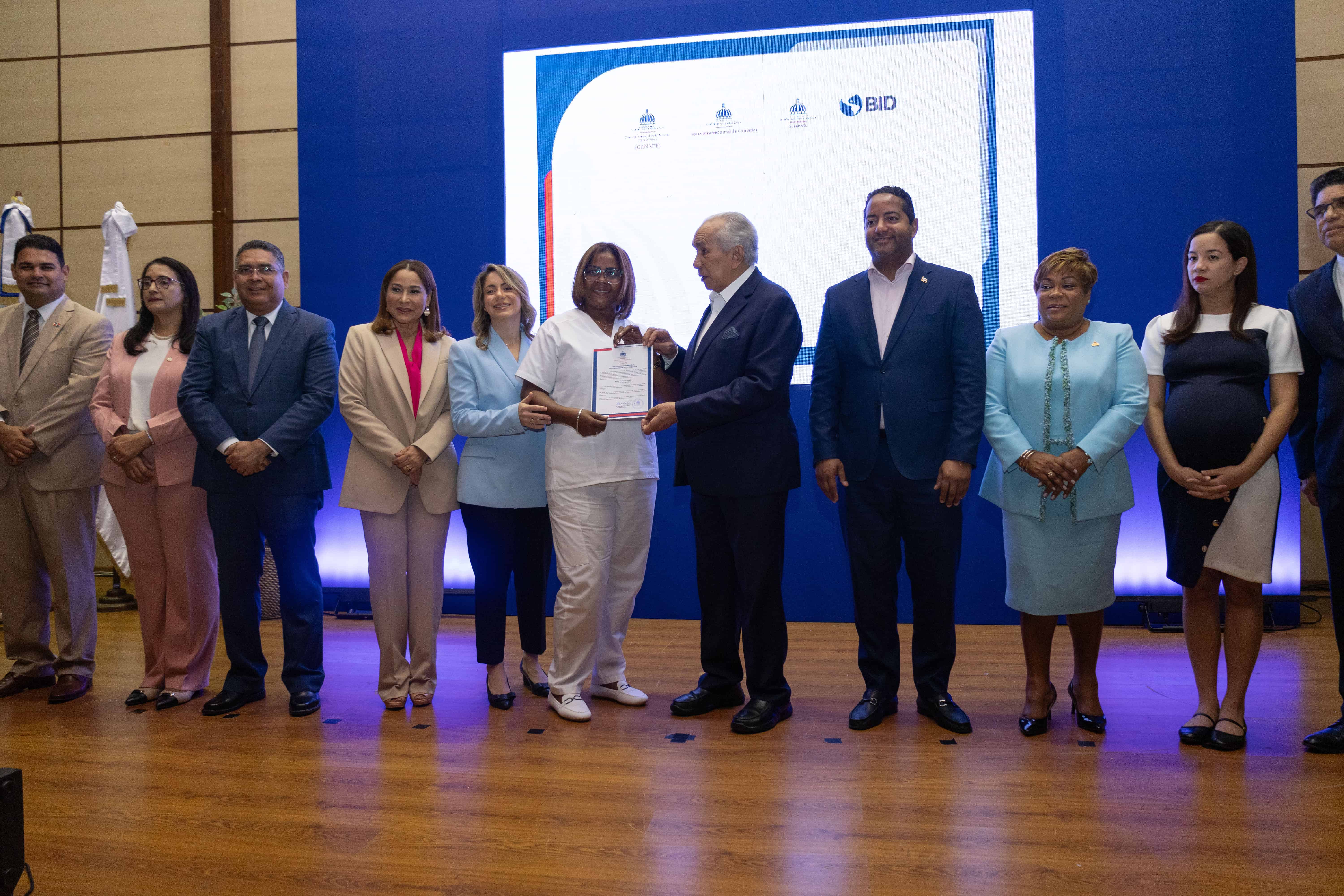 Entregan certificado a una de las graduadas del programa de capacitación para el cuidado de envejecientes.