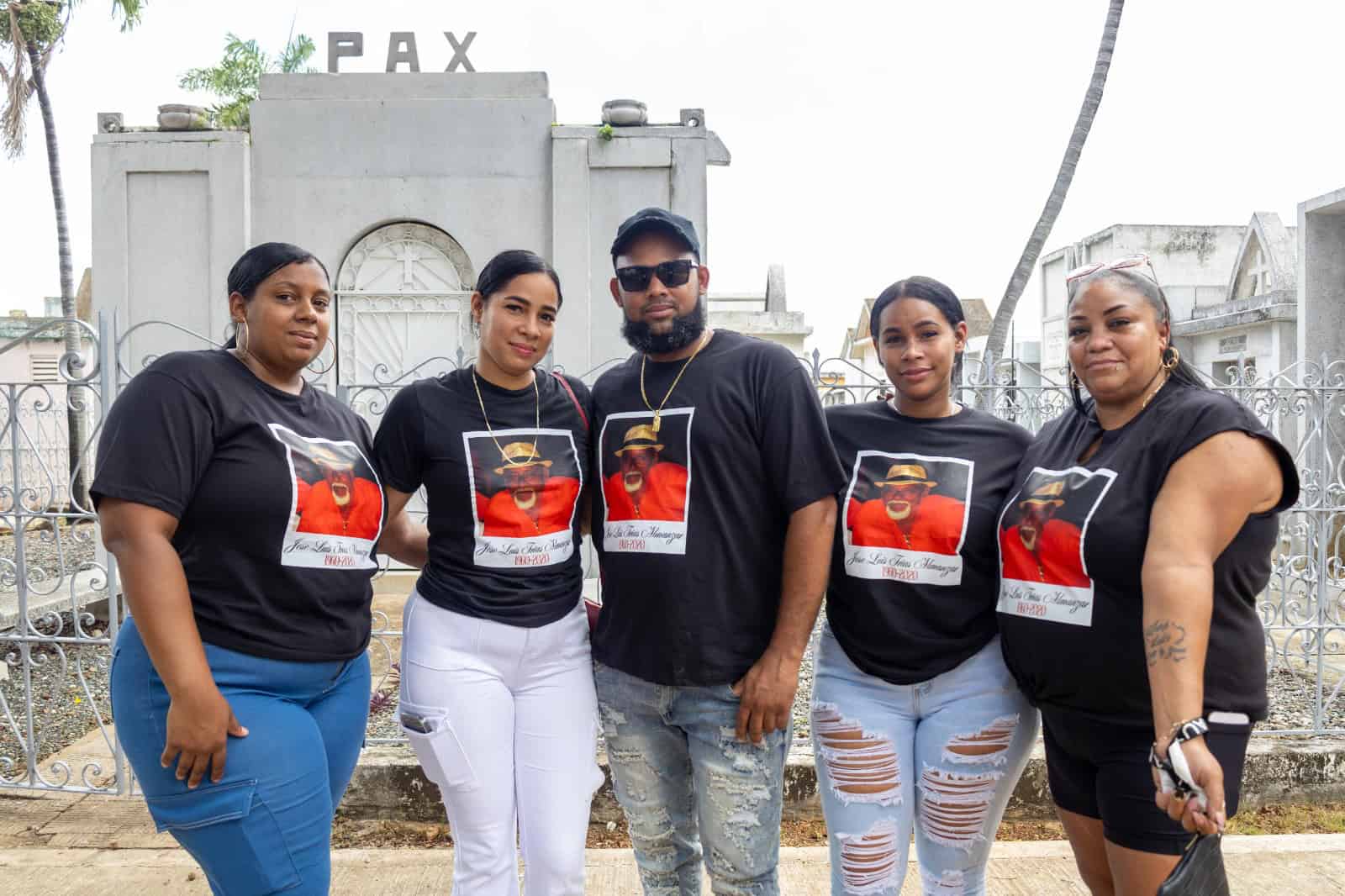 Hijos posan con camiseta y fotografía de su padre.