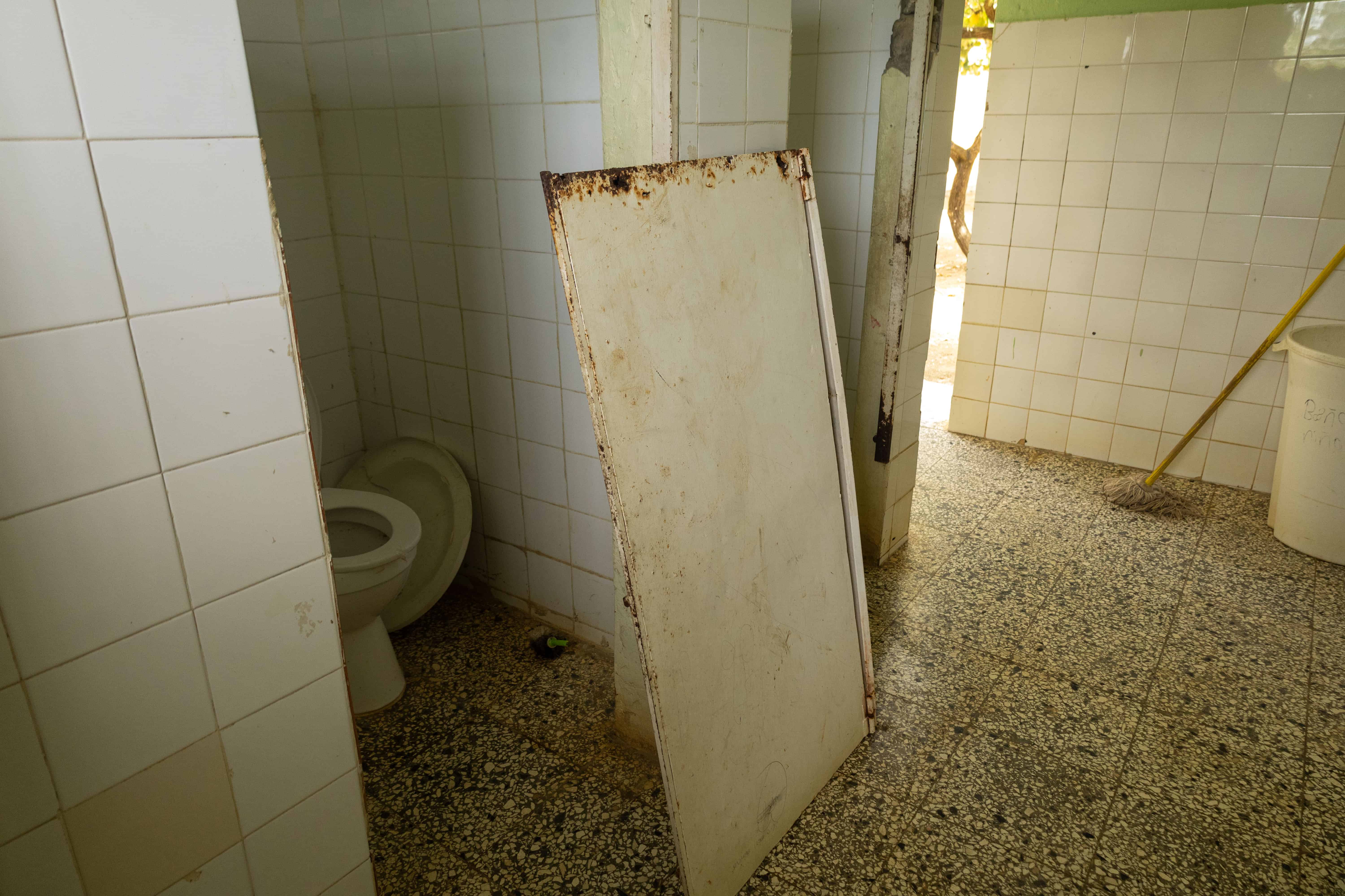 Falta mantenimiento en los baños, que tienen puertas despegadas y corroídas