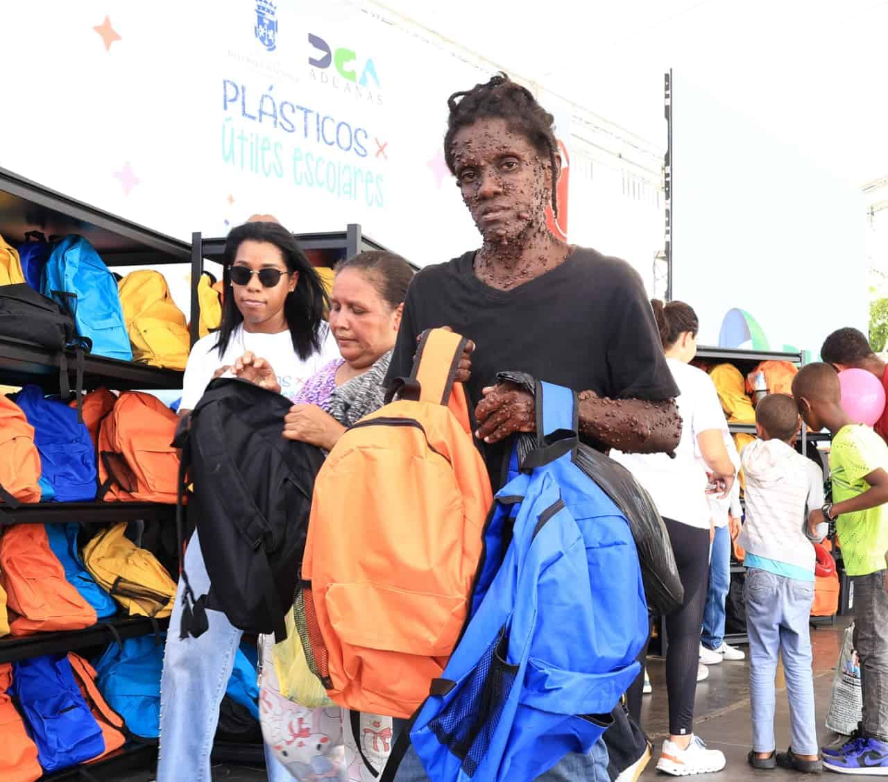 Una mujer muestra los útiles escolares entregados.