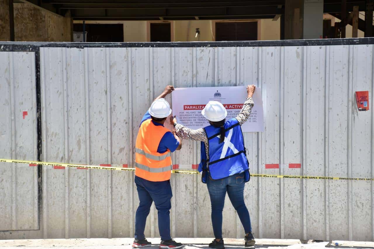 Personal del Ministerio de Trabajo coloca un letrero en una construcción intervenida.