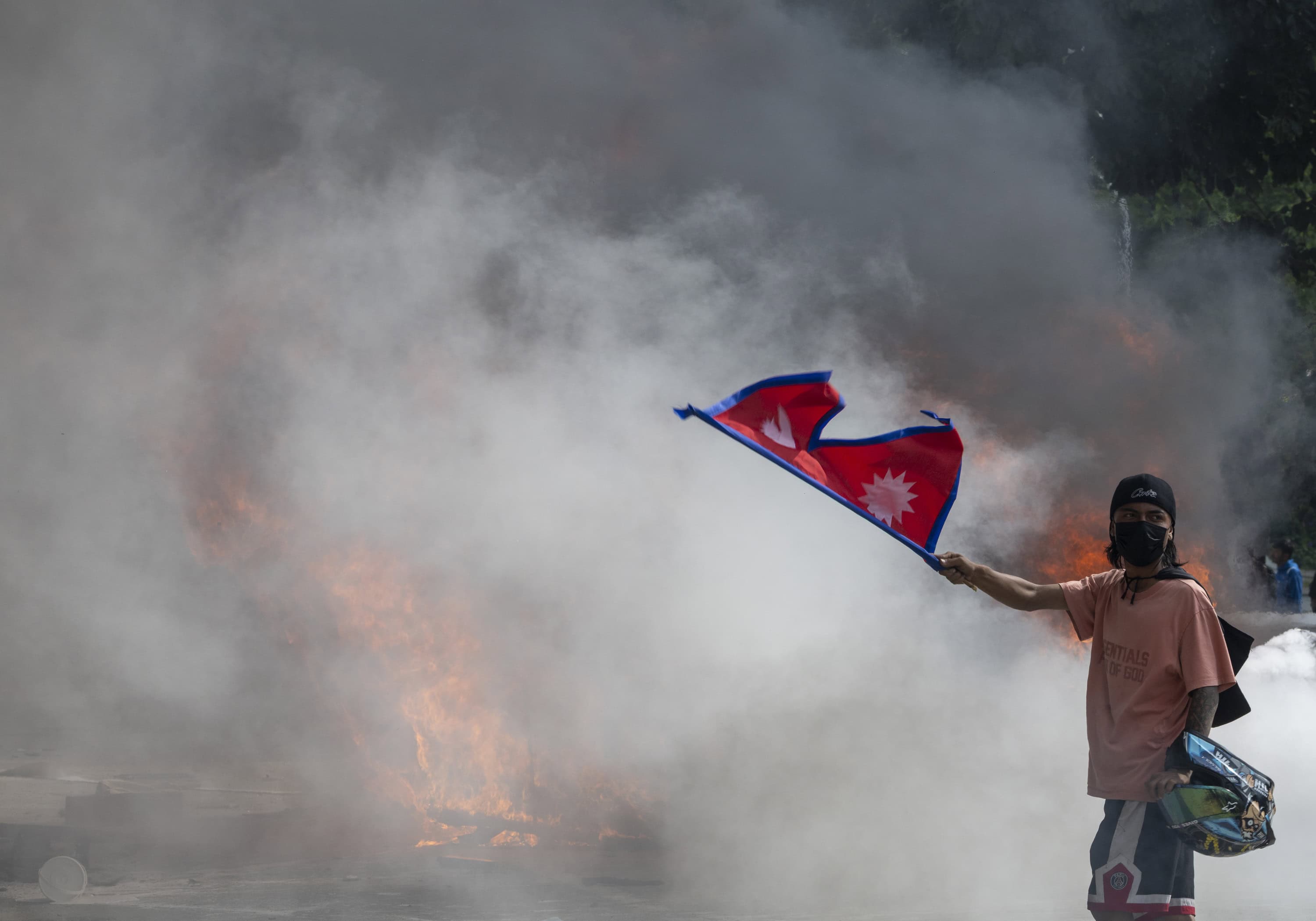 A man wave the national flag of Nepal near smoke and fire at the Singha Durbar palace, which houses government and parliament buildings, after protesters stormed the premises during violent demonstrations in Kathmandu, Nepal, 09 September 2025. At least 19 people were killed and dozens injured on 08 September during demonstrations against corruption and a government social media ban. (Protestas)