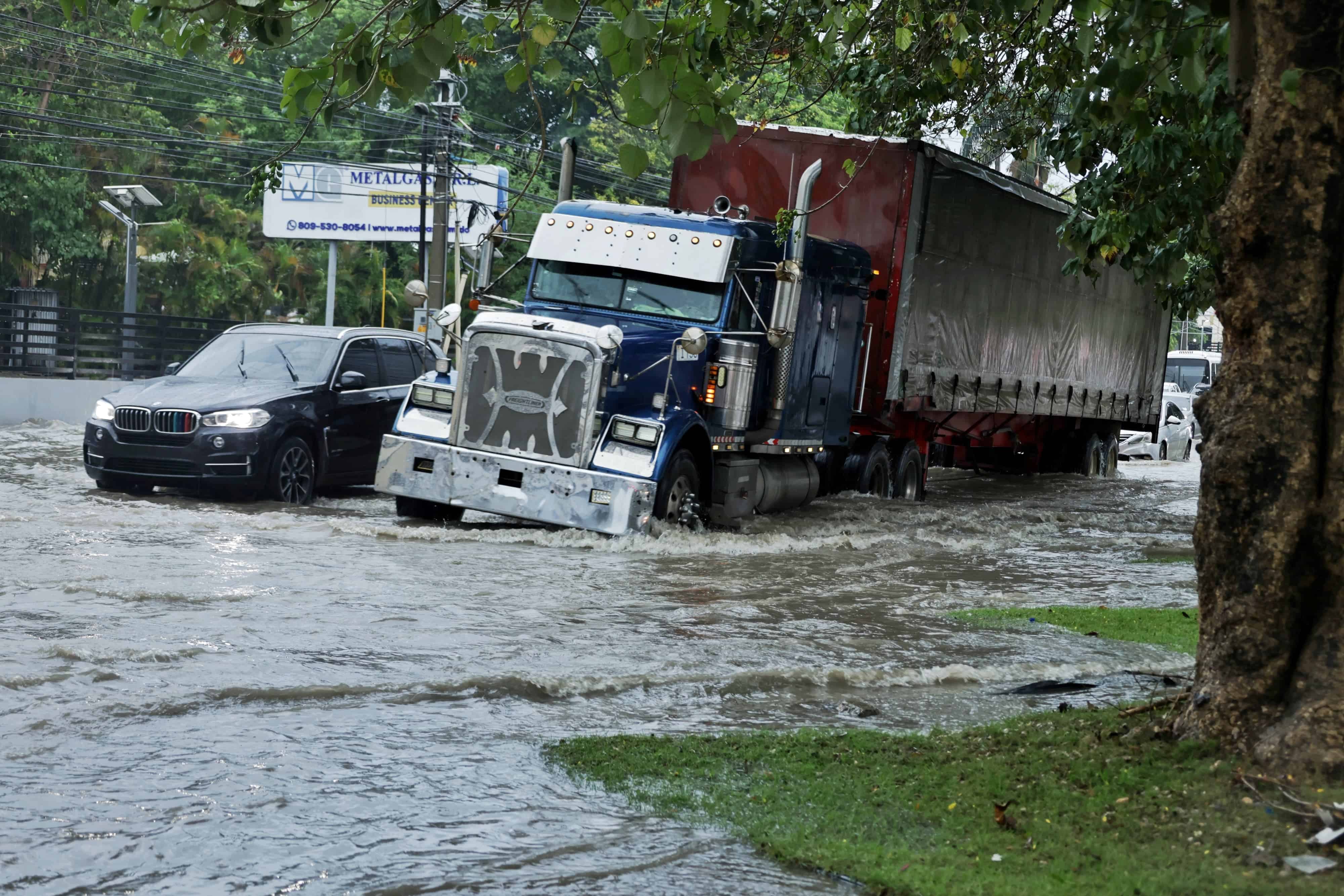Una patana cruza con dificultad la acumulación de agua en la avenida Gregorio Luperón.