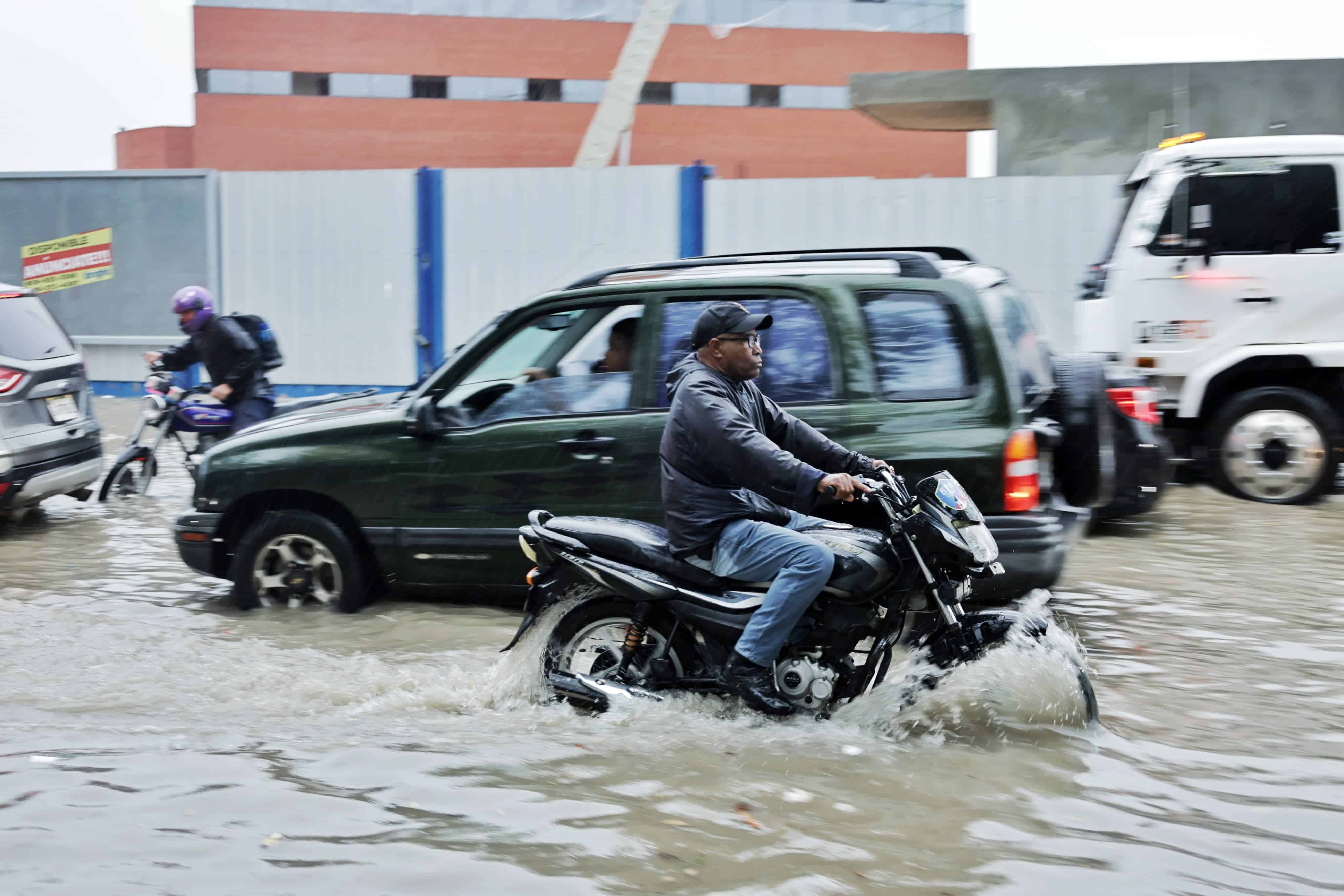 A bordo de un motor, y conduciendo en vía contraria, un hombre trata de evitar un gran charco en la avenida Gregorio Luperón.