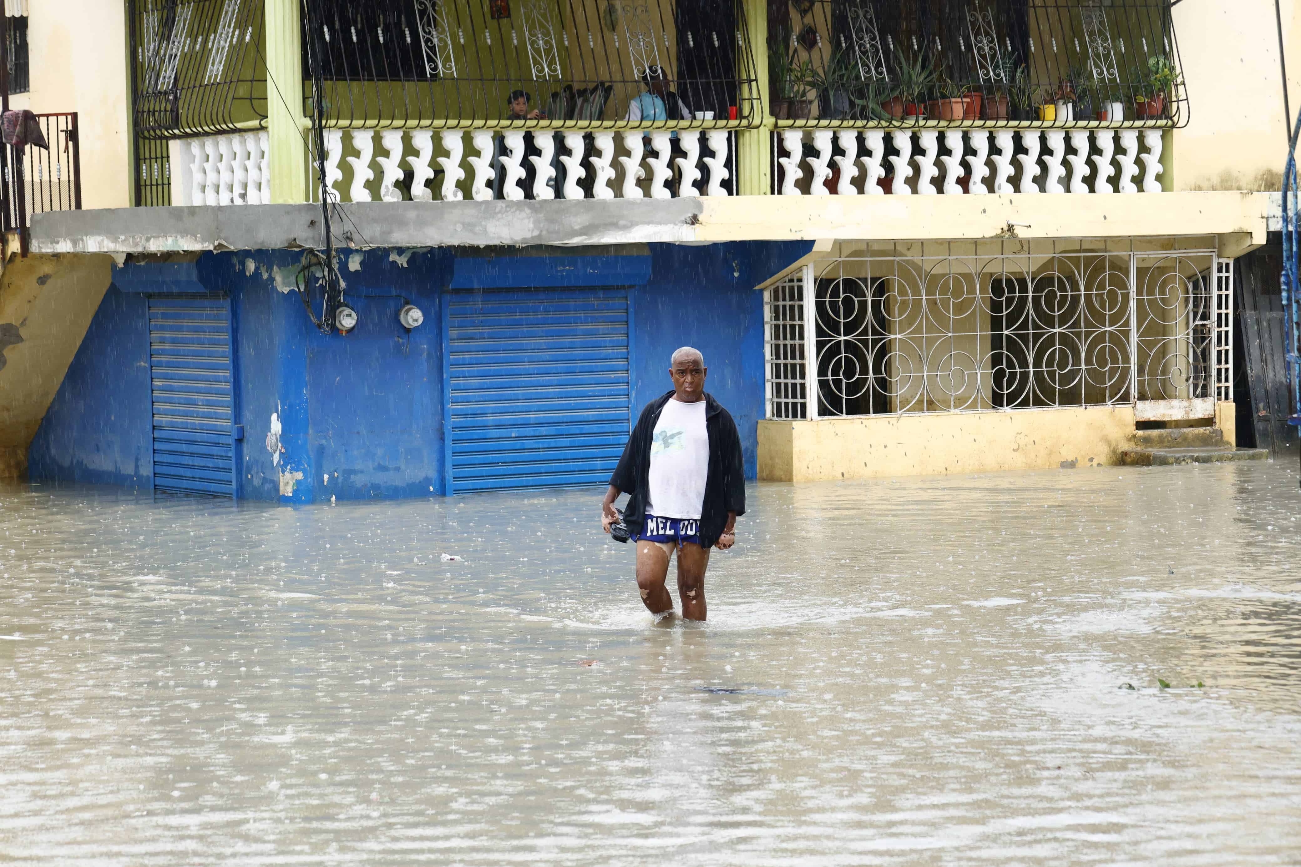 Un hombre cruza una calle con  el agua a la altura de las rodillas en el sector Manoguayabo.
