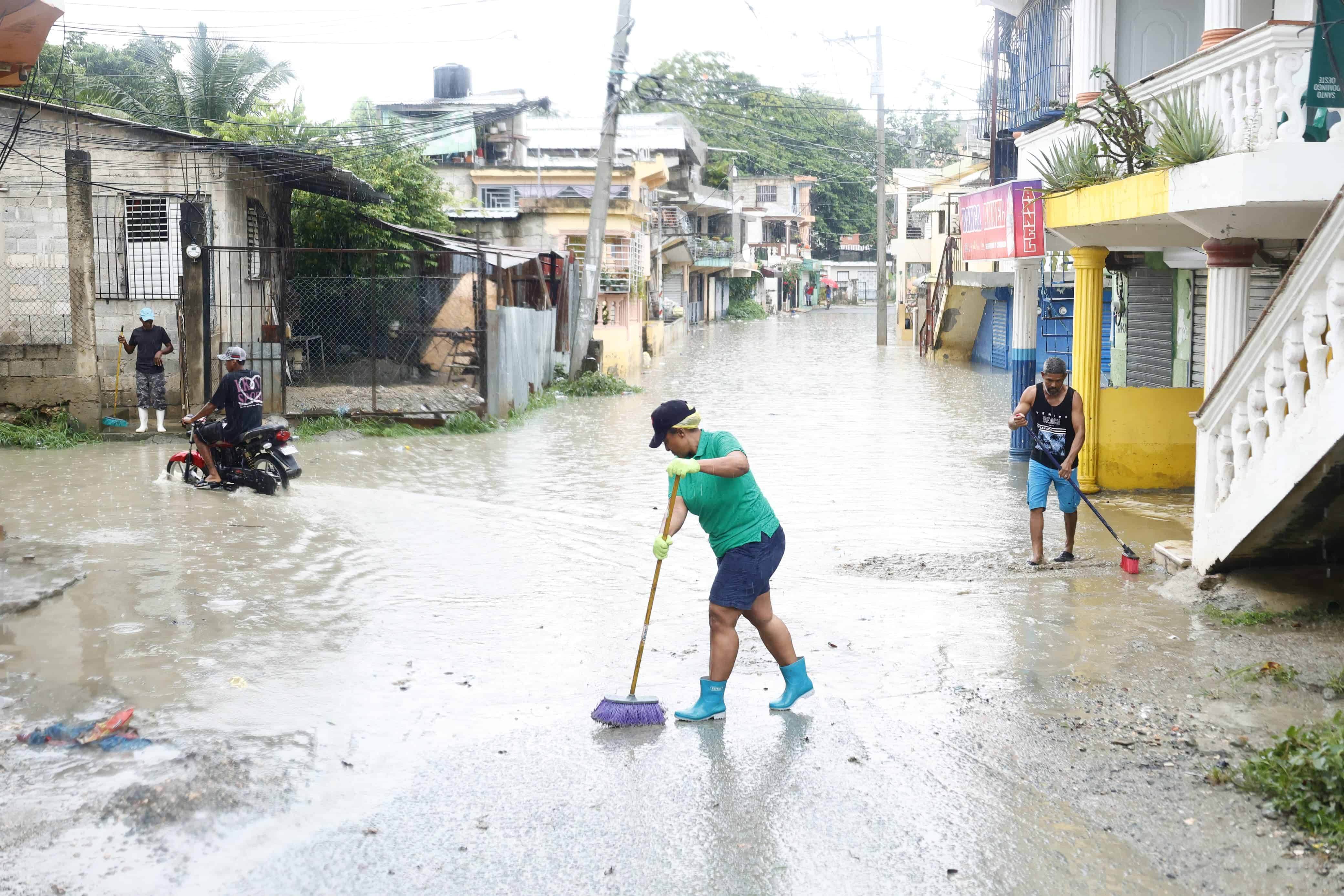 Armada con una escoba una mujer intenta hacer retroceder las aguas en una calle del sector Manoguayabo