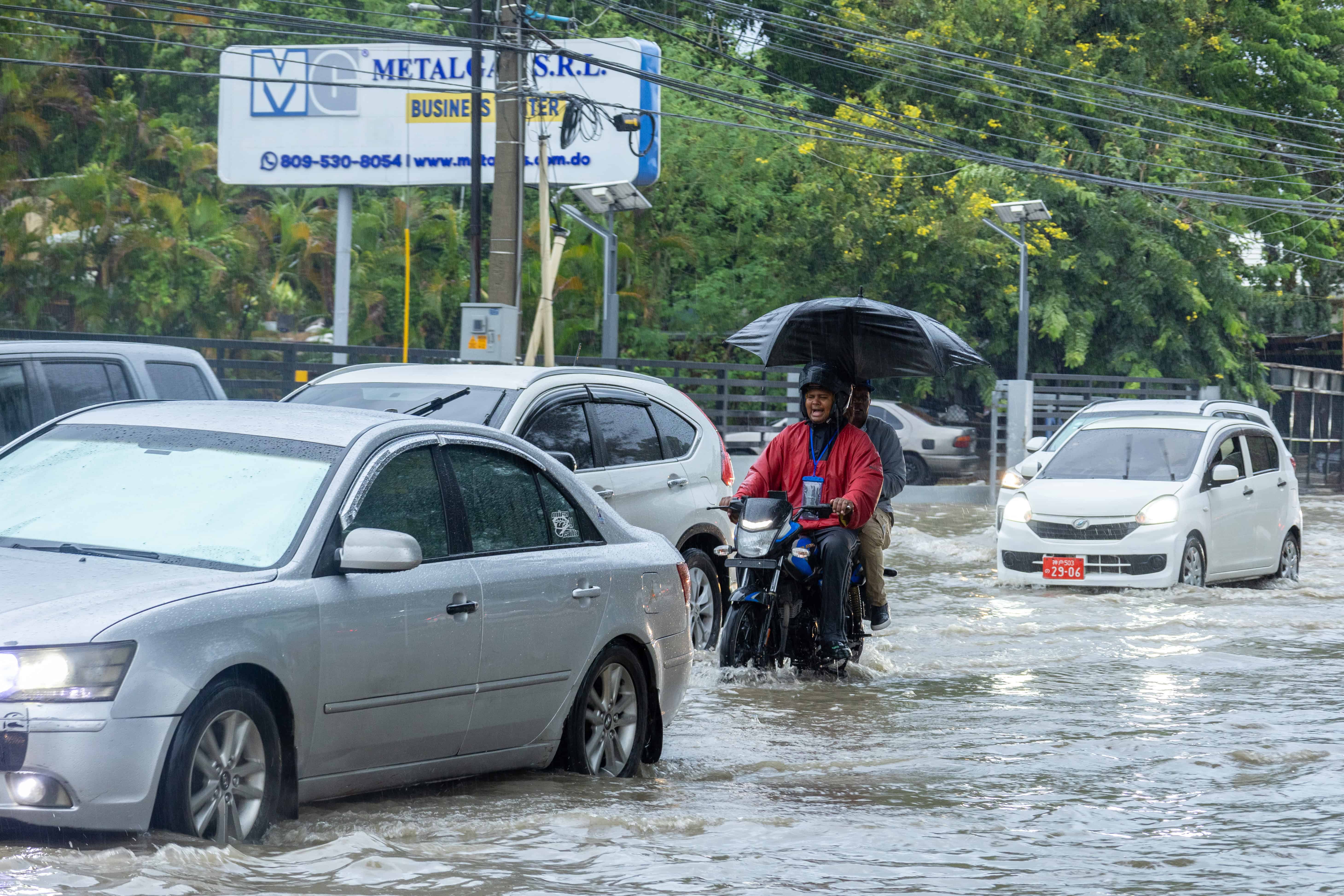 Dos personas en una motocicleta atraviesan un charco en la capital. 