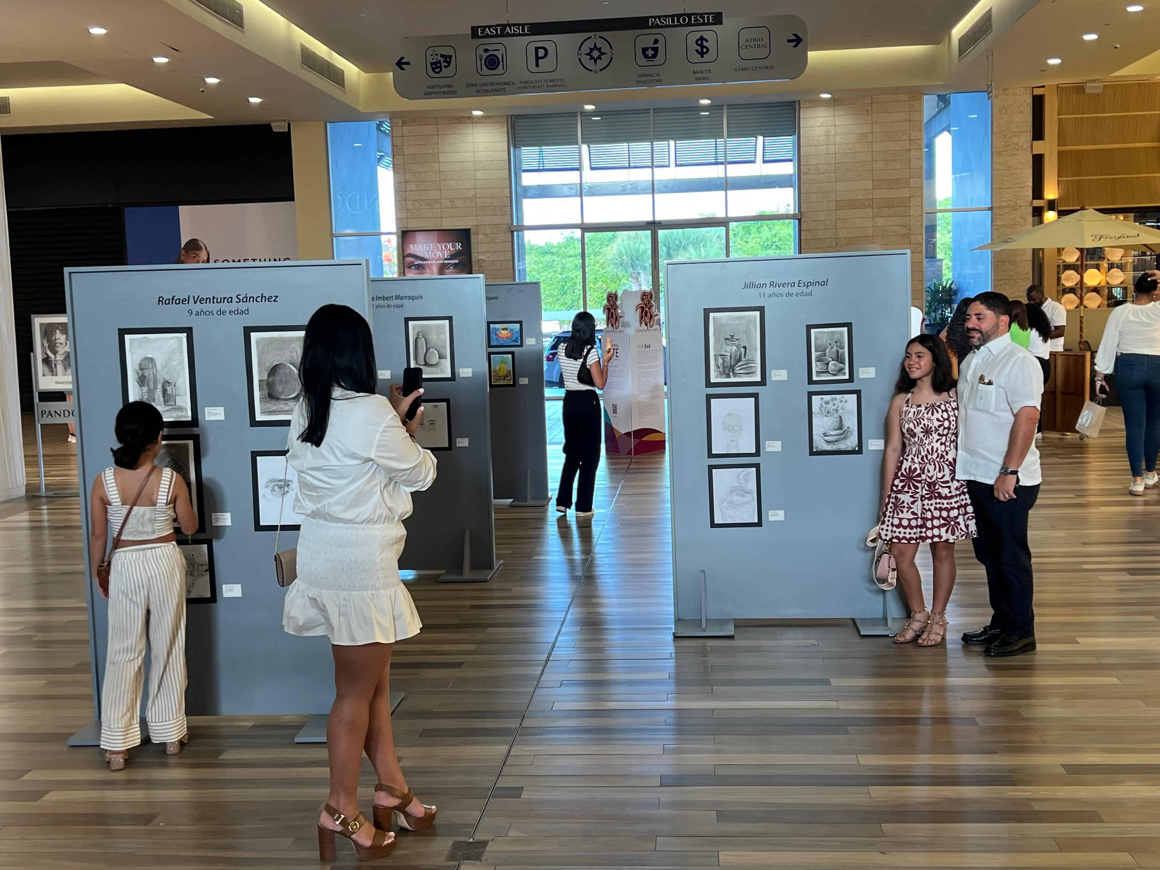Participantes y familiares disfrutan de las obras durante la apertura de la exposición "Gato de París 2025" en BlueMall Puntacana.