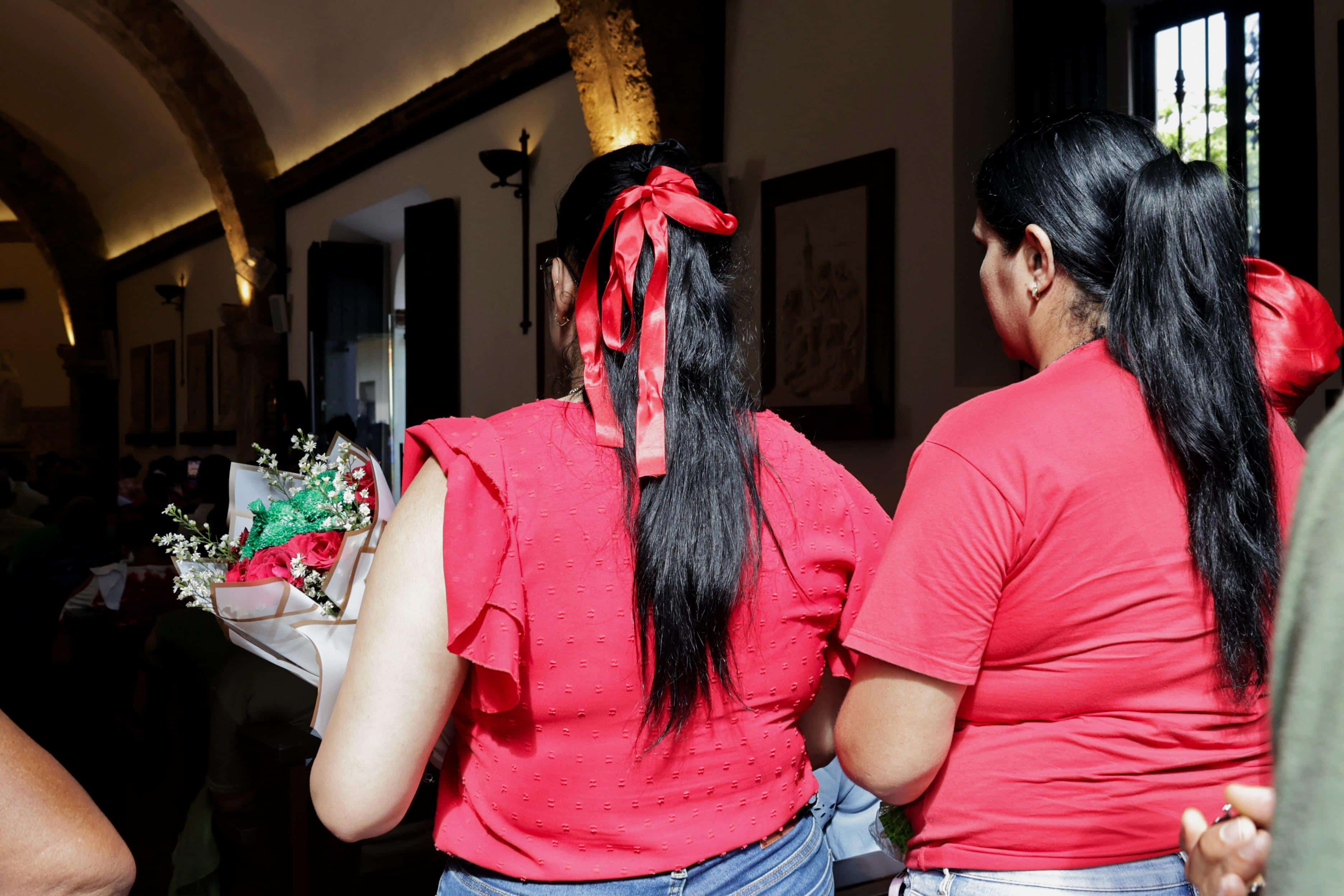 Dos devotas ingresan a la iglesia San Miguel en la Ciudad Colonial con flores como ofrenda.