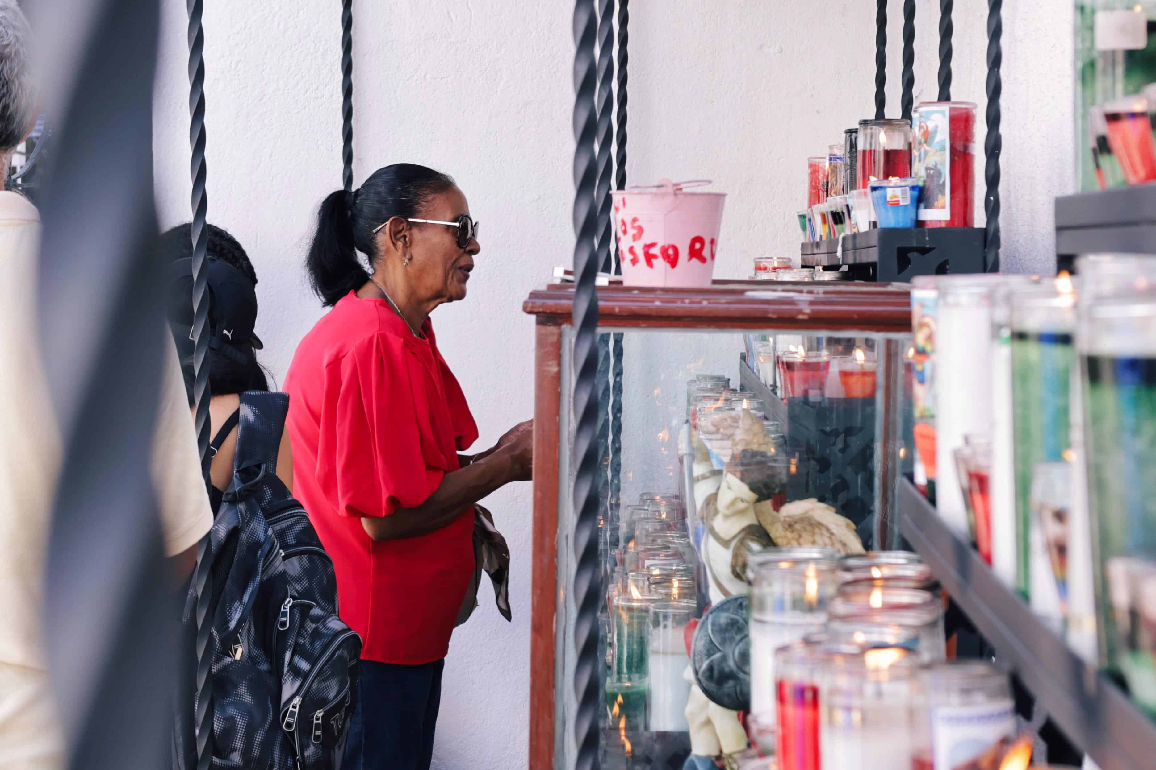 Un mujer frente a un altar en honor al arcángel Miguel.