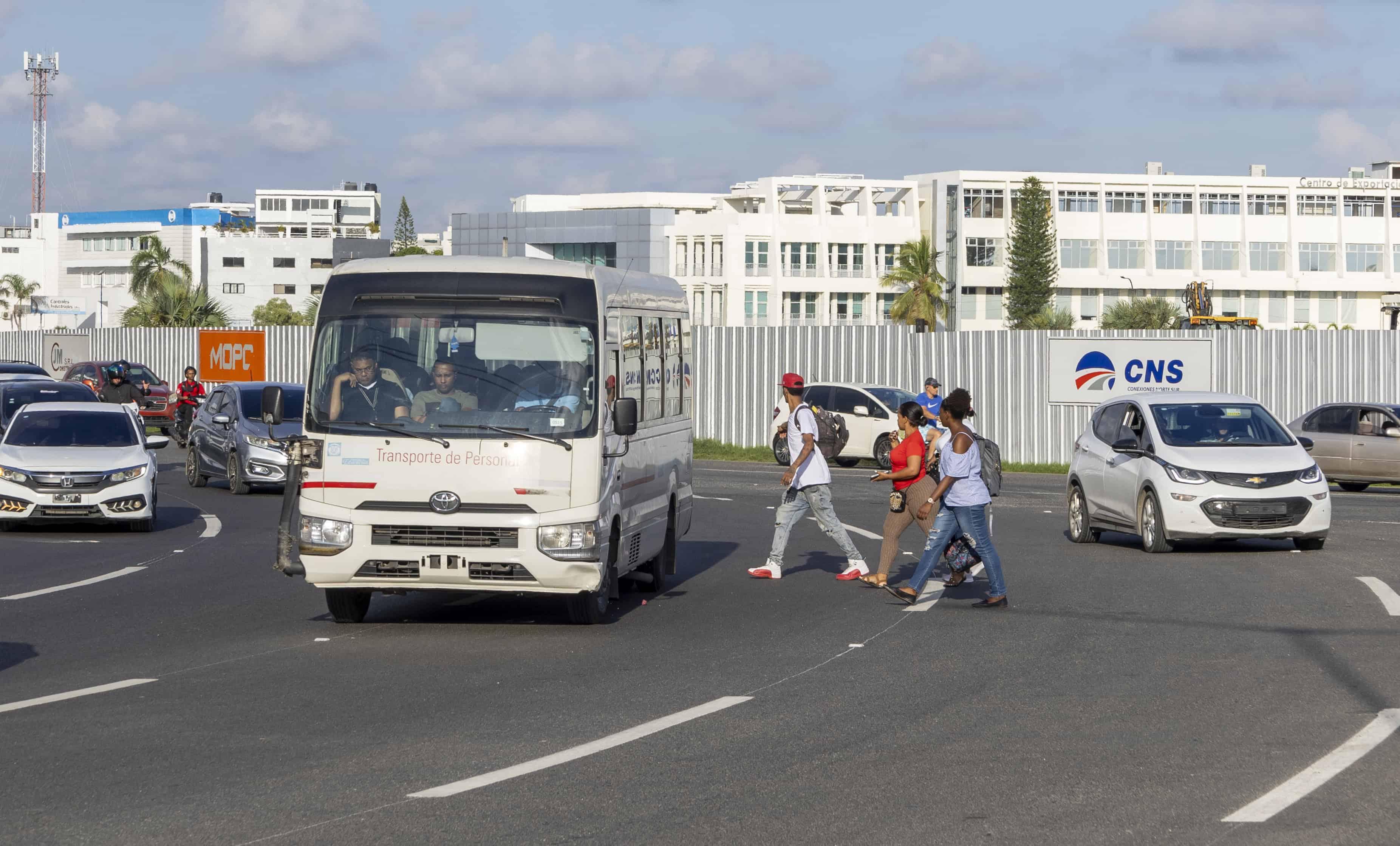 Ciudadanos intentando cruzar entre los vehículos.