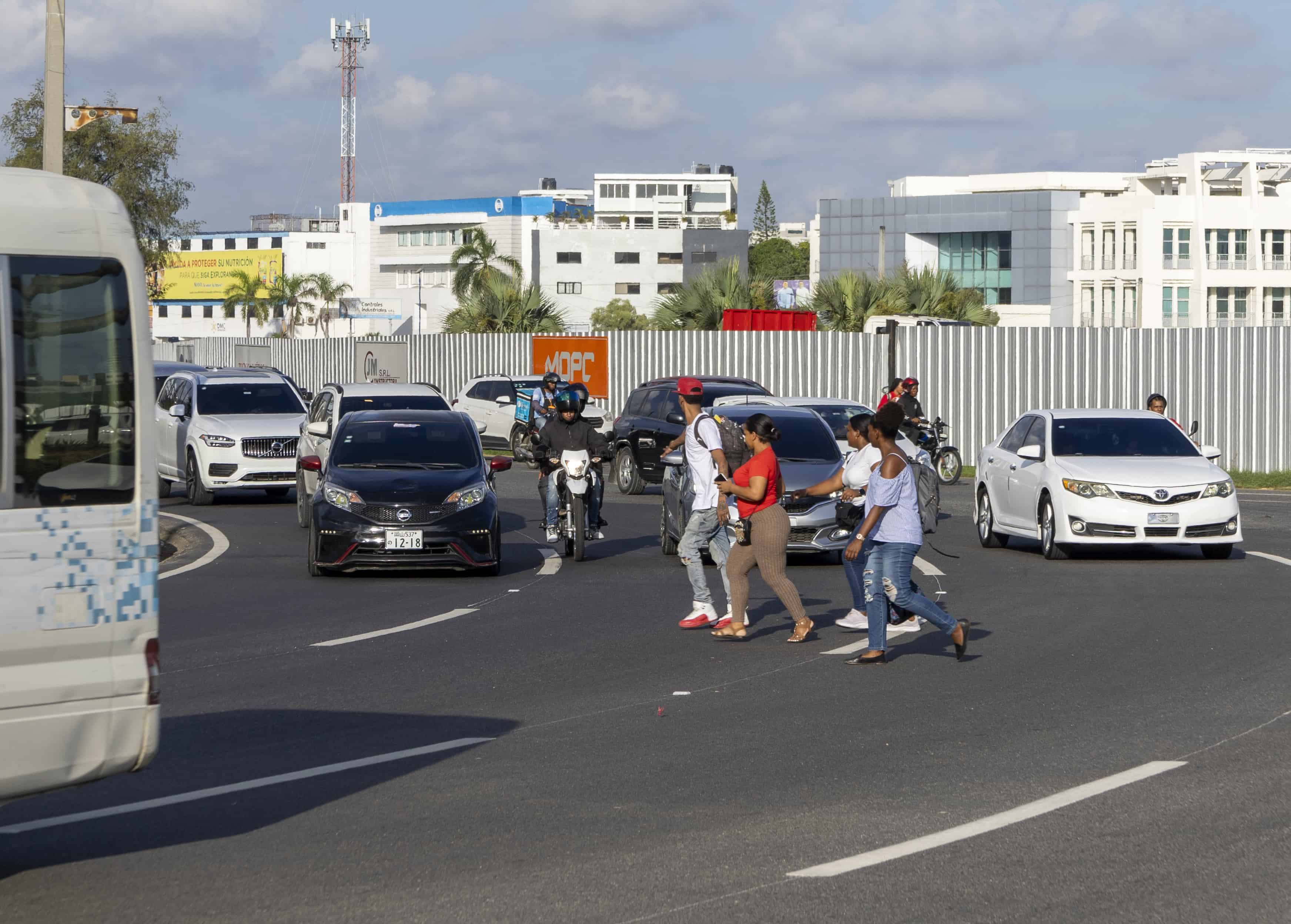 Ciudadanos intentando cruzar entre los vehículos.