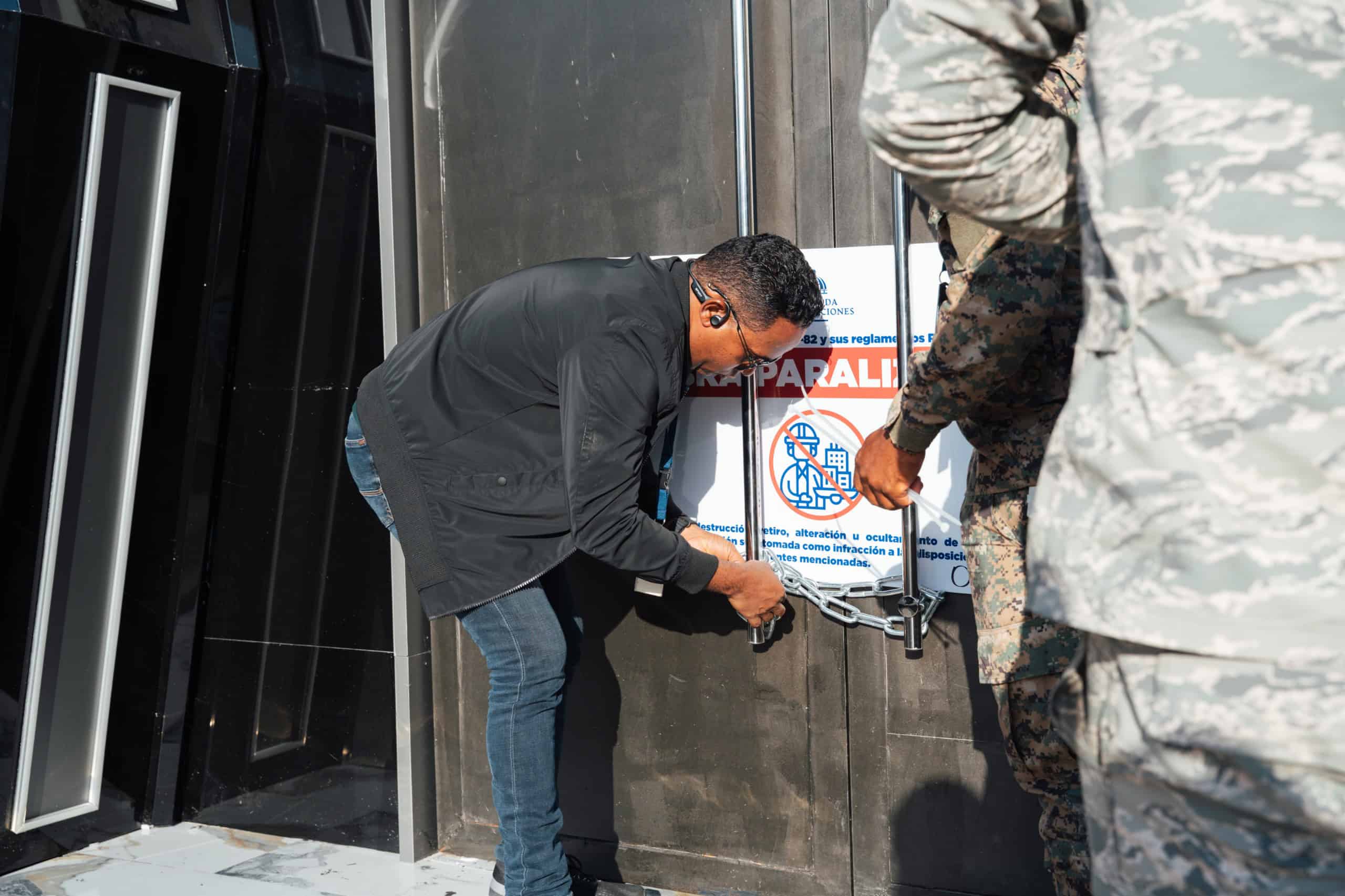 Un hombre coloca un candado a la puerta del centro de diversión. 