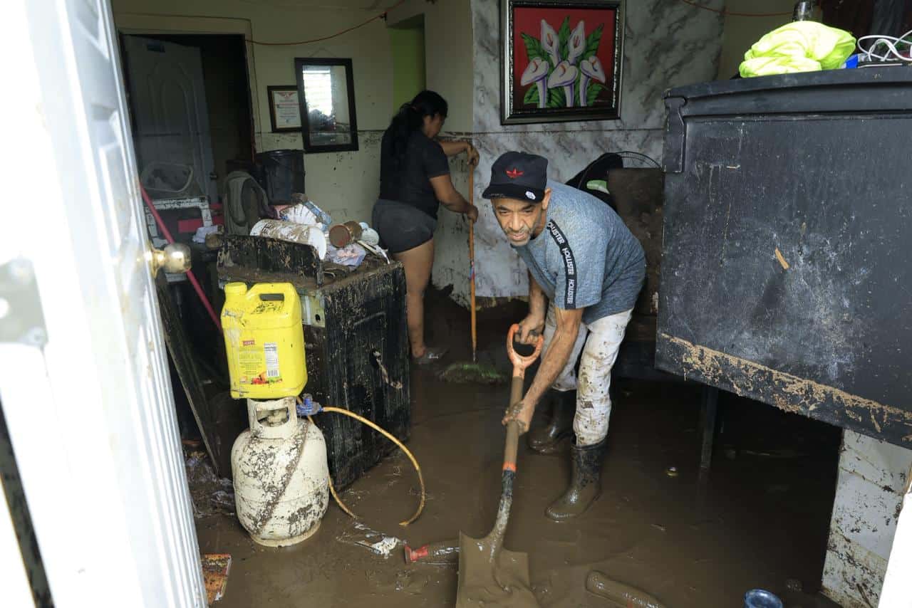 Karla Villalona y su vecino Alberto Sánchez ayudando a sacar el lodo de la casa.